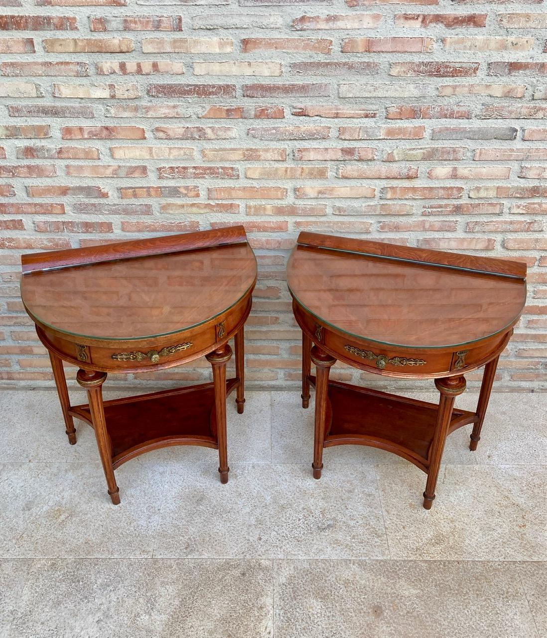 Beautiful pair of 1930s empire style mahogany nightstands. 
They are shaped like a half moon and two legs give elegance and typical style of their time. They also have a central drawer ideal for storing small items. 
It also has a very practical