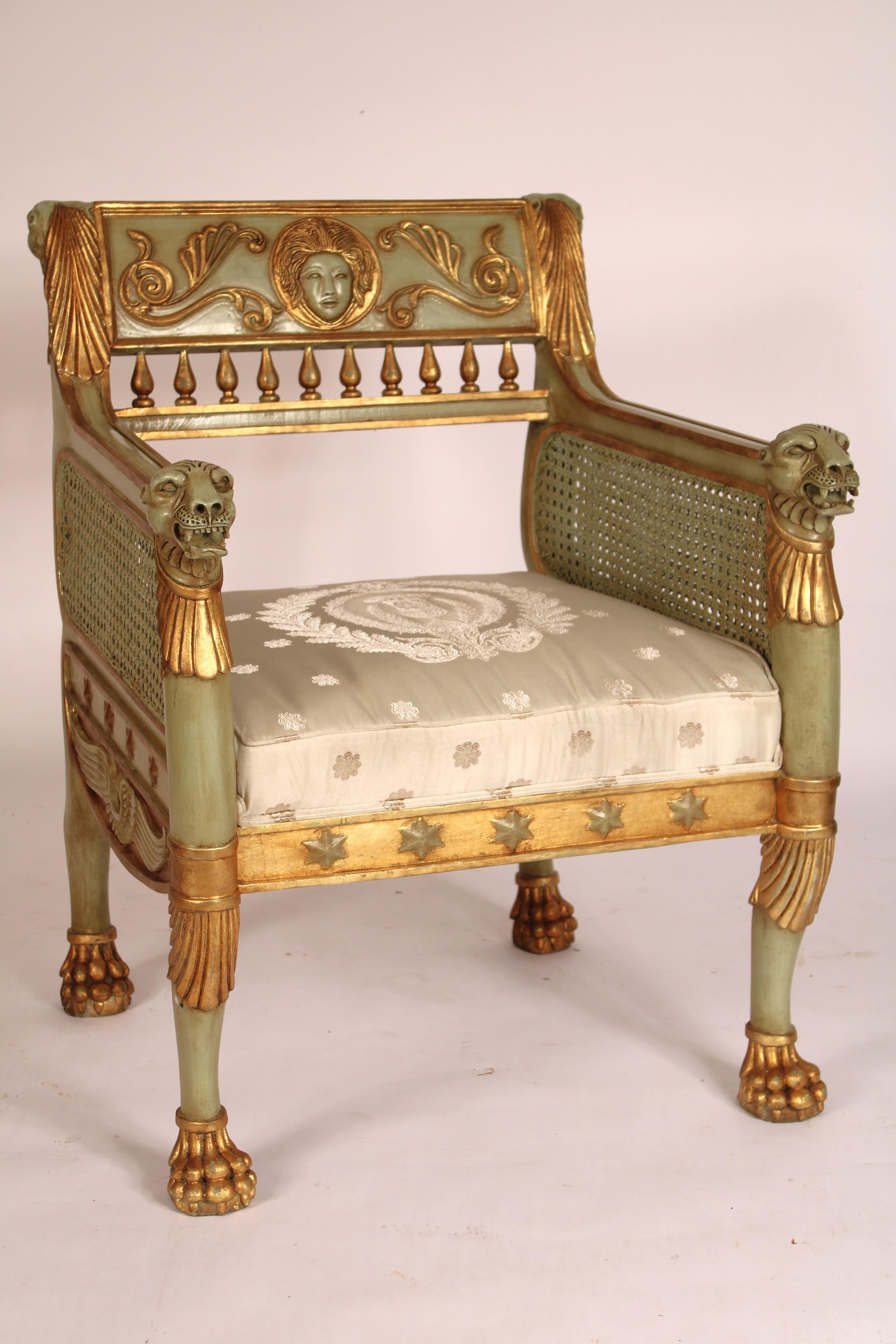 Pair of Egyptian Empire style painted and gilt decorated bergeres, late 20th century. The crest rail with a central carved face flanked by scrolling gilt vines  the back of the crest rail with carved lion heads on each side, below the crest rail are