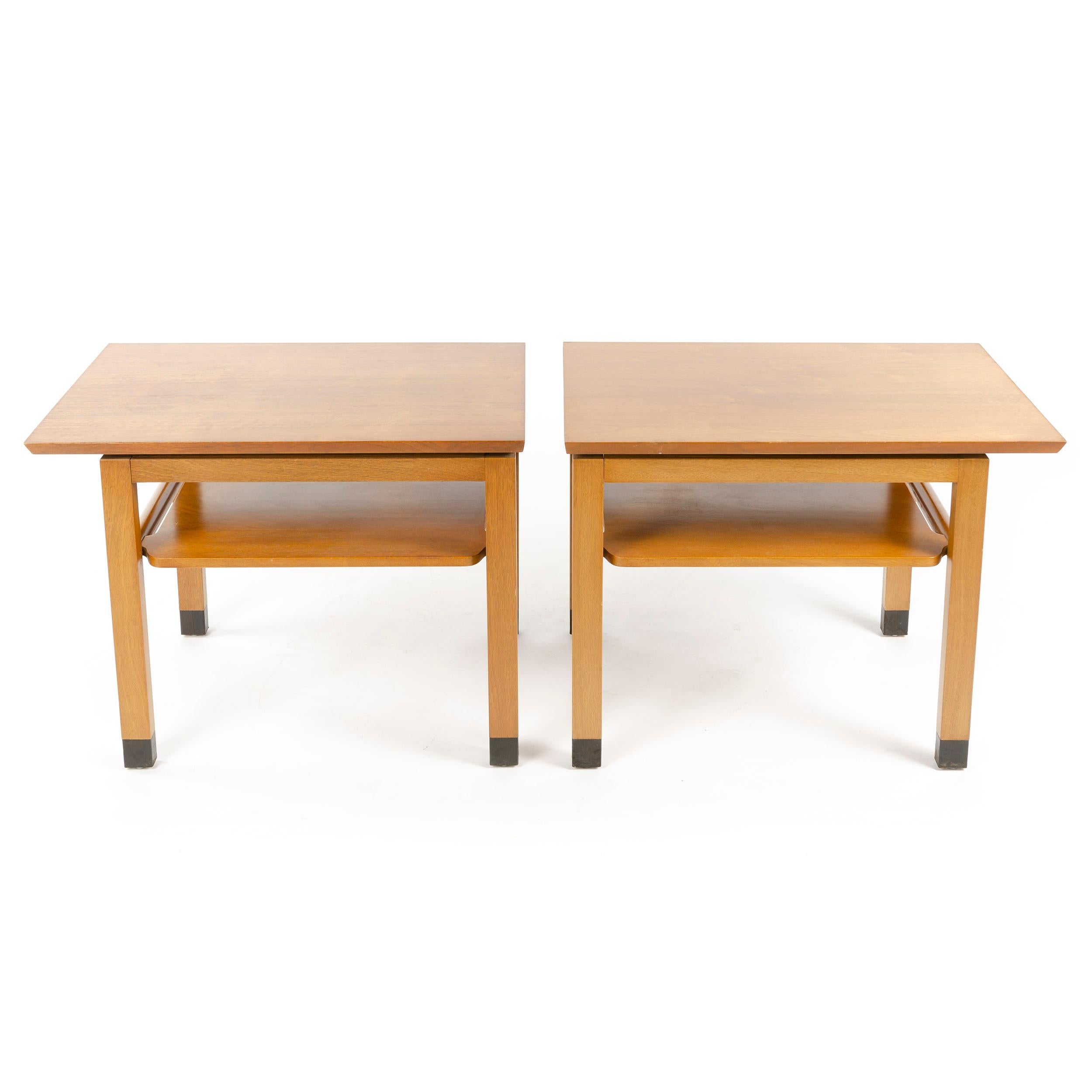 A set of two (2) Mid-Century Modern end tables designed by Edward Wormley, each with a cantilevered top over a shelf and leather wrapped feet. Made by Dunbar in the USA, circa 1950s.