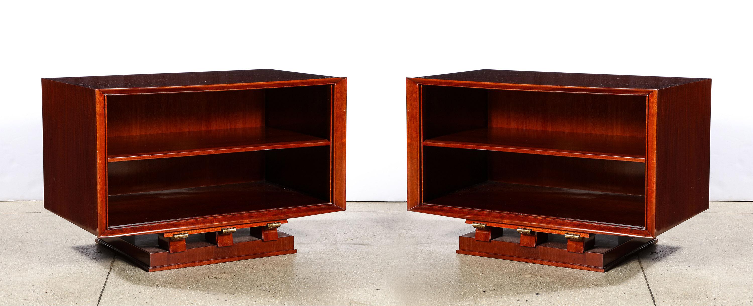 The pair of tables / cabinets, each with an adjustable shelf, having a framed front and atop a rectangular plinth with gilded bronze accents. 

Each signed on back 