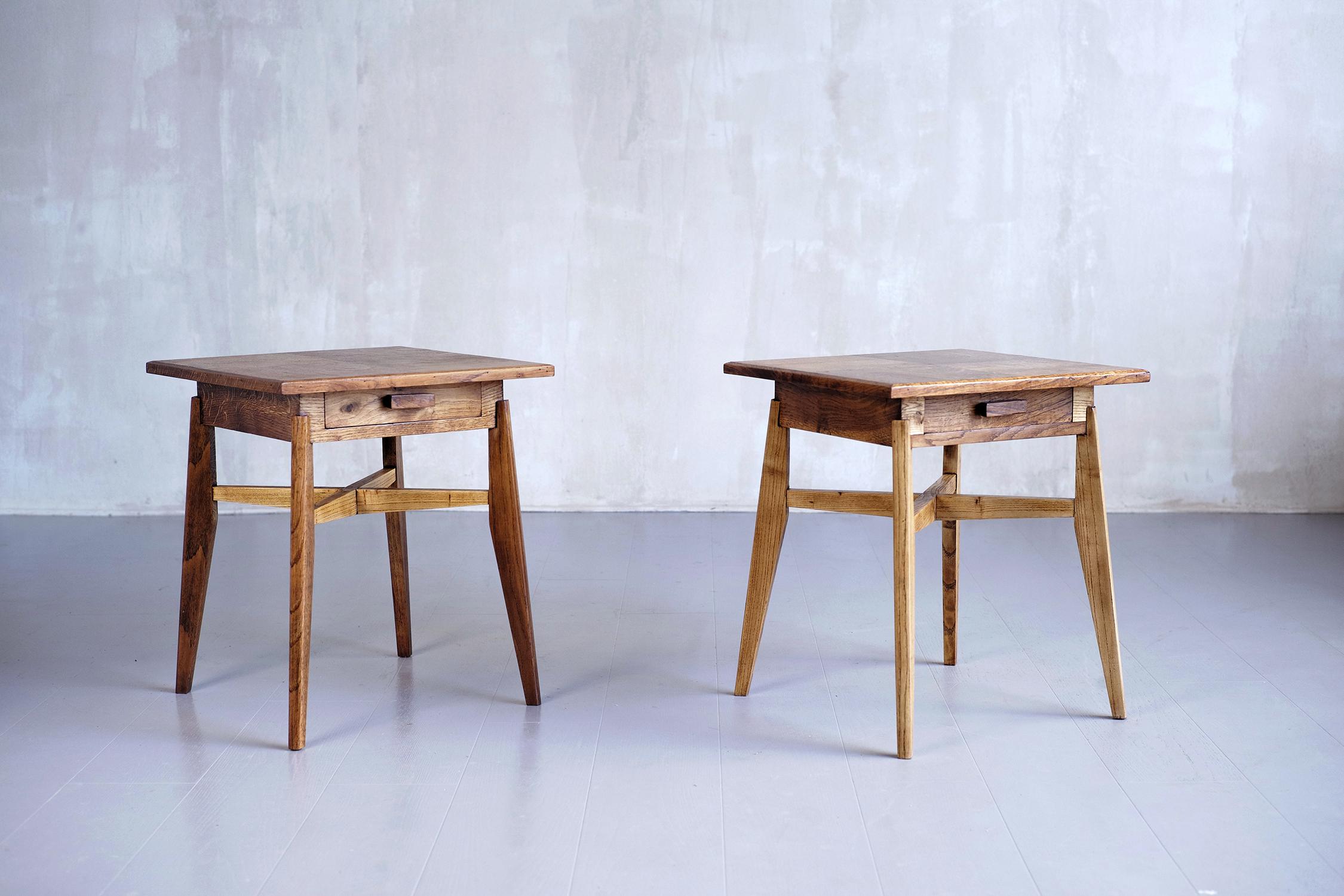 Pair of oak side tables, French Reconstruction 1950. Can be used at the end of the sofa or as bedside tables, these pretty tables have a cross-braced base, a belt drawer and a top adorned with a checkerboard veneer. The period of the French