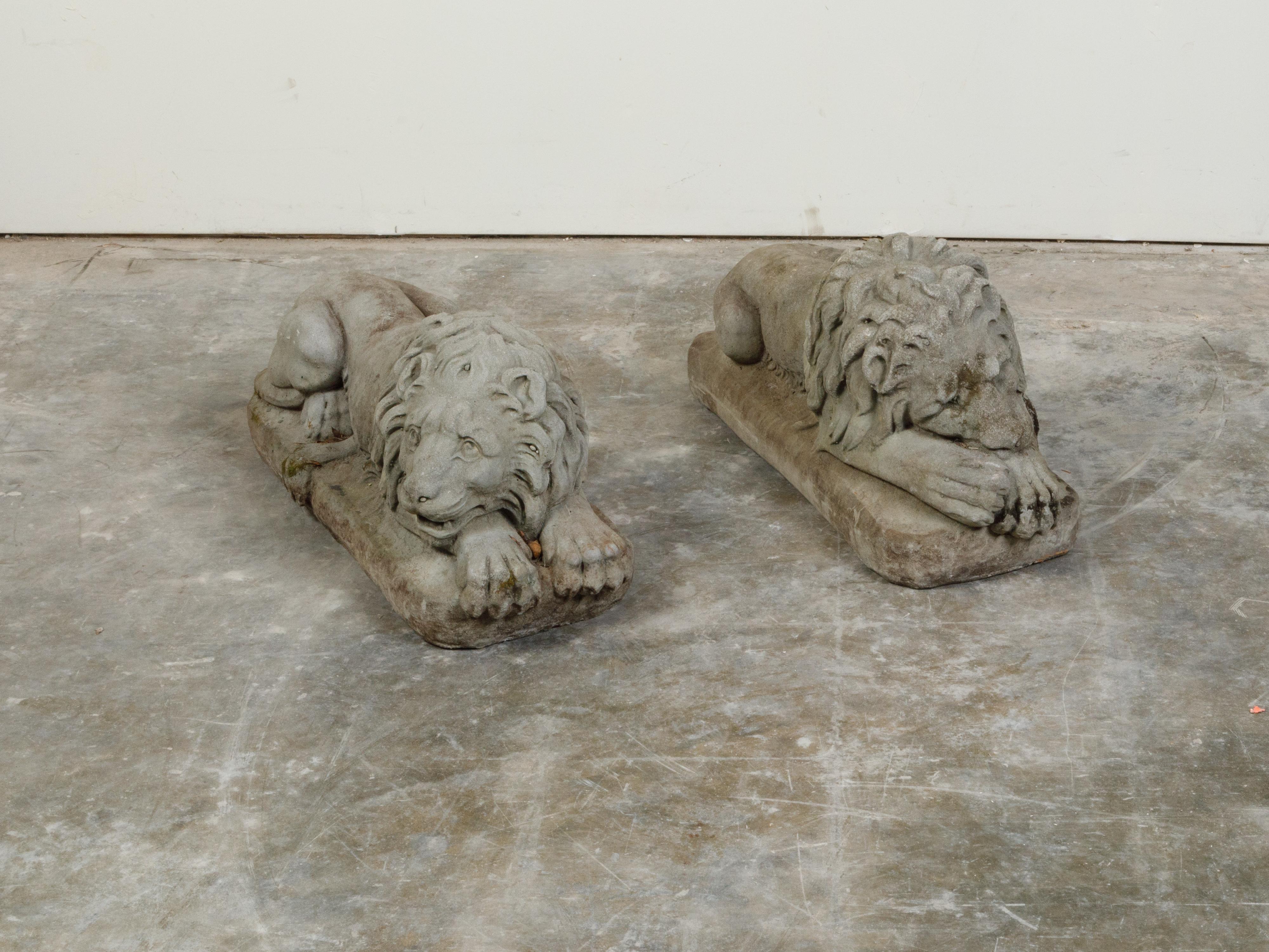 20th Century Pair of English 1920s Cast Stone Reclining Lion Sculptures on Conforming Bases For Sale