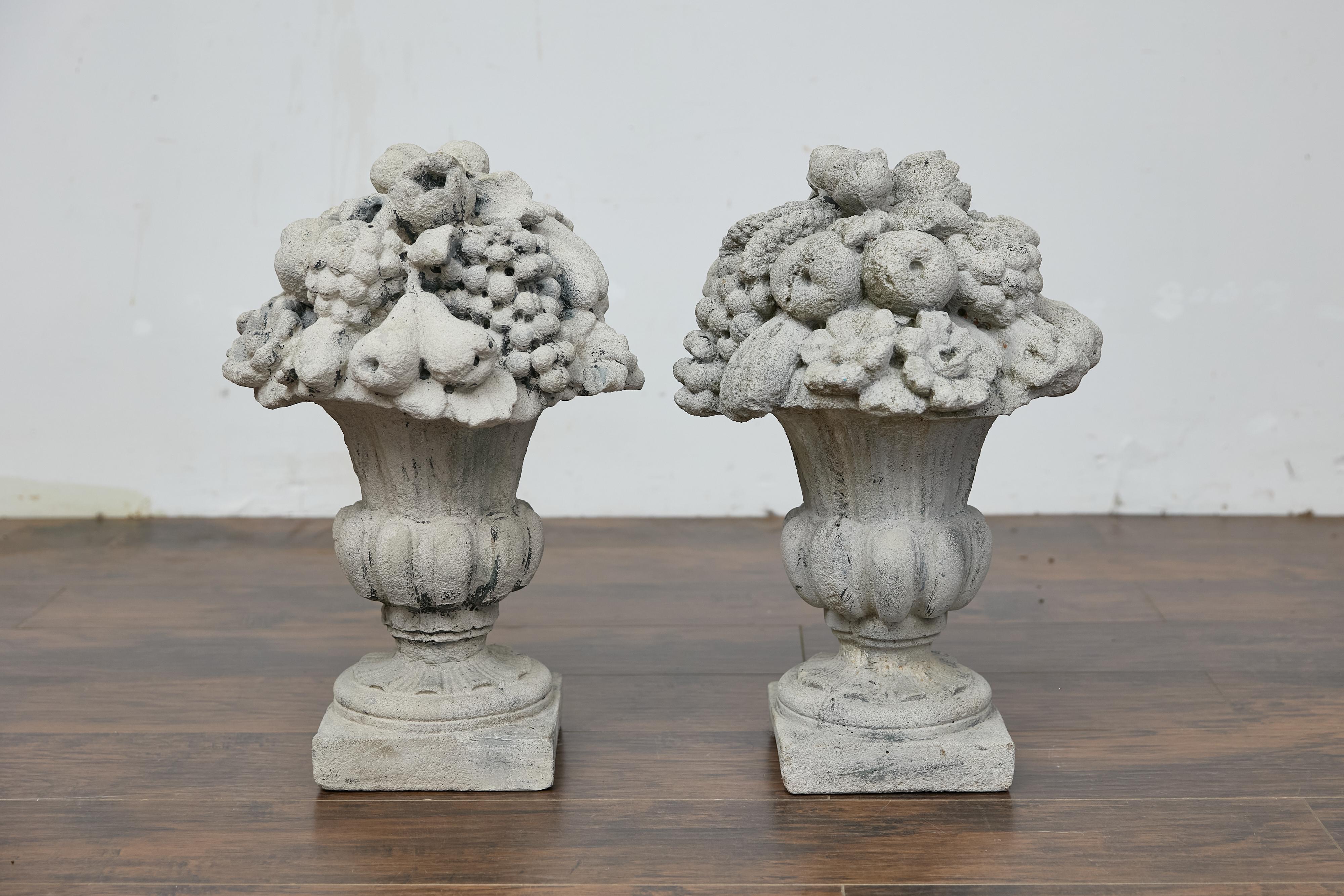 Paire d'urnes anglaises en pierre moulée, datant d'environ 1920, avec des motifs de fruits et de fleurs sur des bases carrées. Cette paire d'urnes anglaises en pierre moulée, vers 1920, présente une exquise exposition de fruits et de motifs floraux