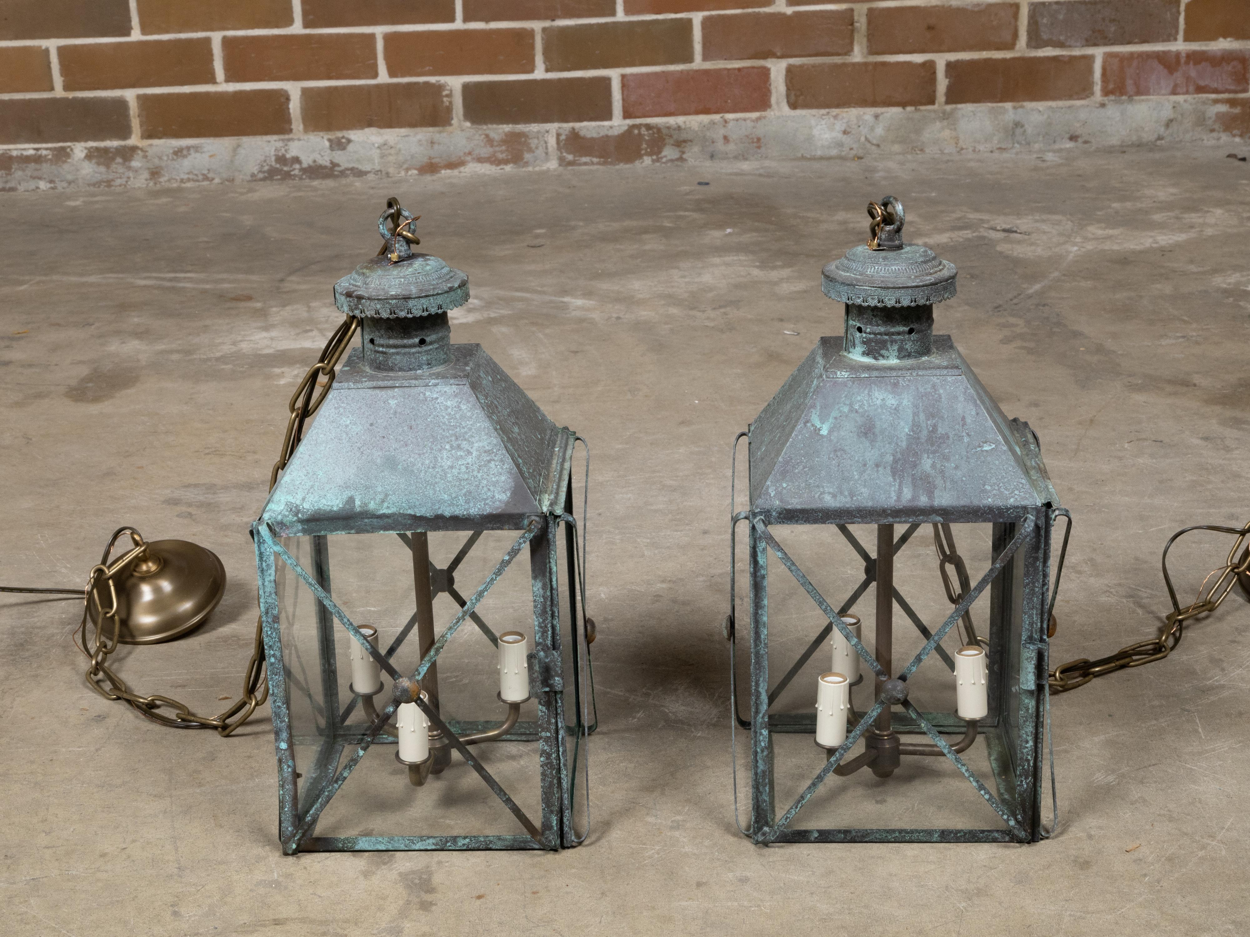 A pair of English three-light copper lanterns from the 19th century with glass panels and verdigris patina. This pair of 19th-century English copper lanterns exudes a timeless charm, enhanced by their beautifully weathered verdigris patina and