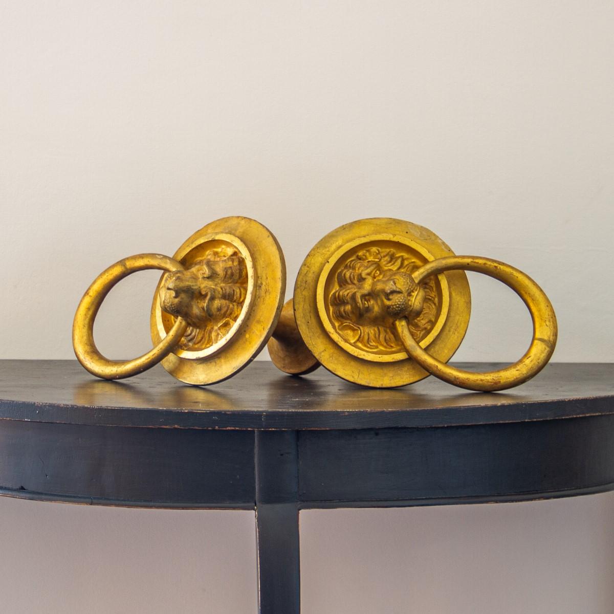 A pair of English giltwood curtain tie backs with beautifully carved lion masks each holding the loop in their mouths, circa 1830.