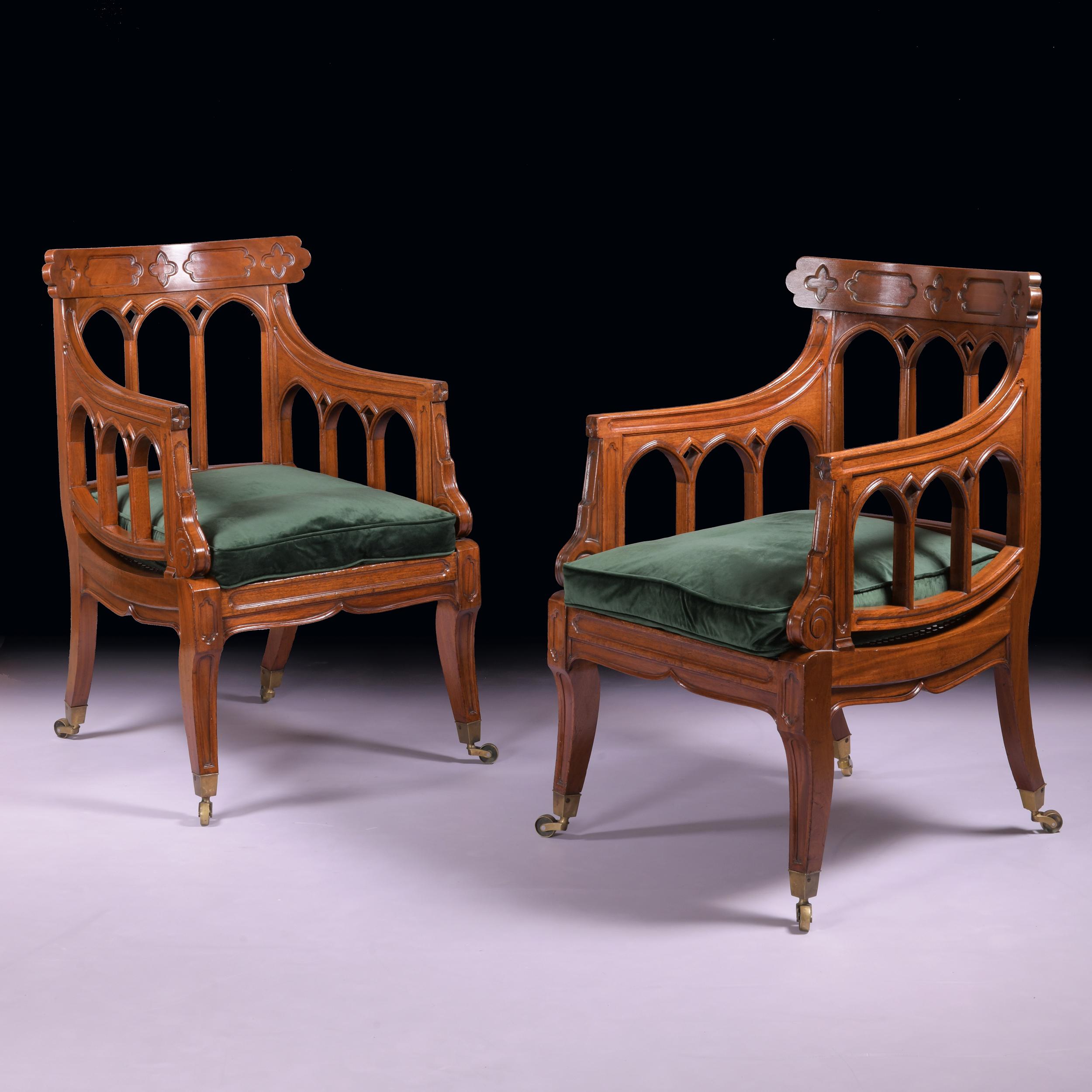 A superb pair of Regency mahogany Gothic revival armchairs in the Manner of William Pordin, the bowed crest rails, centred by quatrefoils, above Gothic arches, conforming down swept channelled arms, deep caned seat, on panelled legs, with brass box