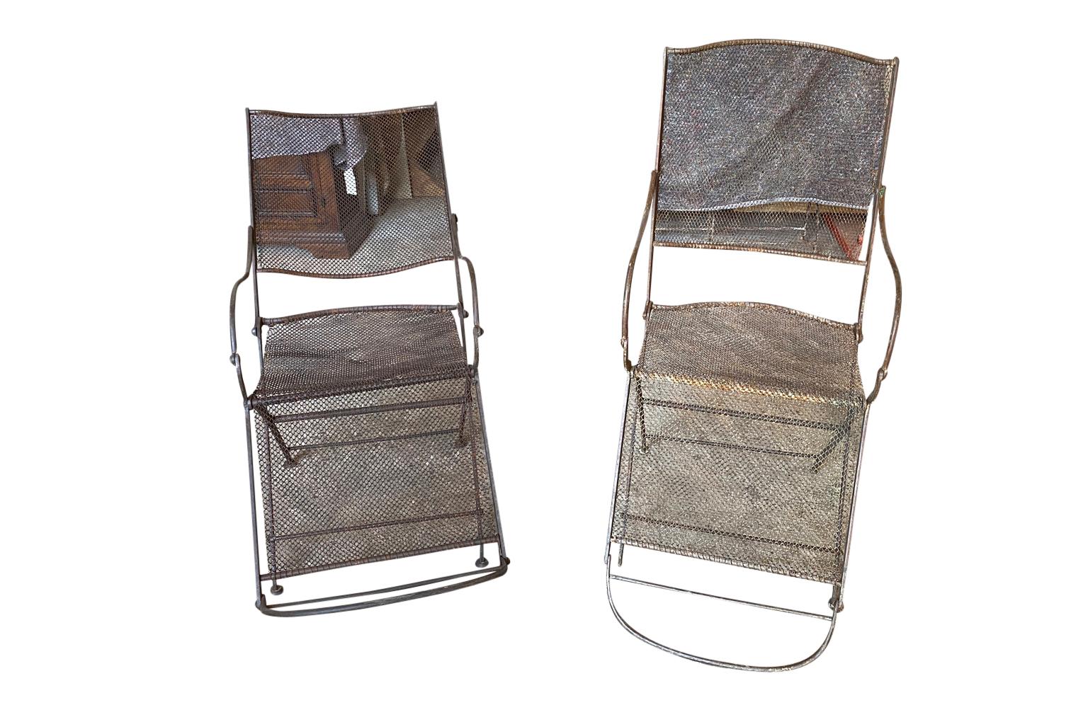 A sensational pair of English 19th century Garden Arm Chairs. Soundly constructed from iron with iron mesh netting backs and seats. The chairs comfortably recline. Terrific for any garden or interior.