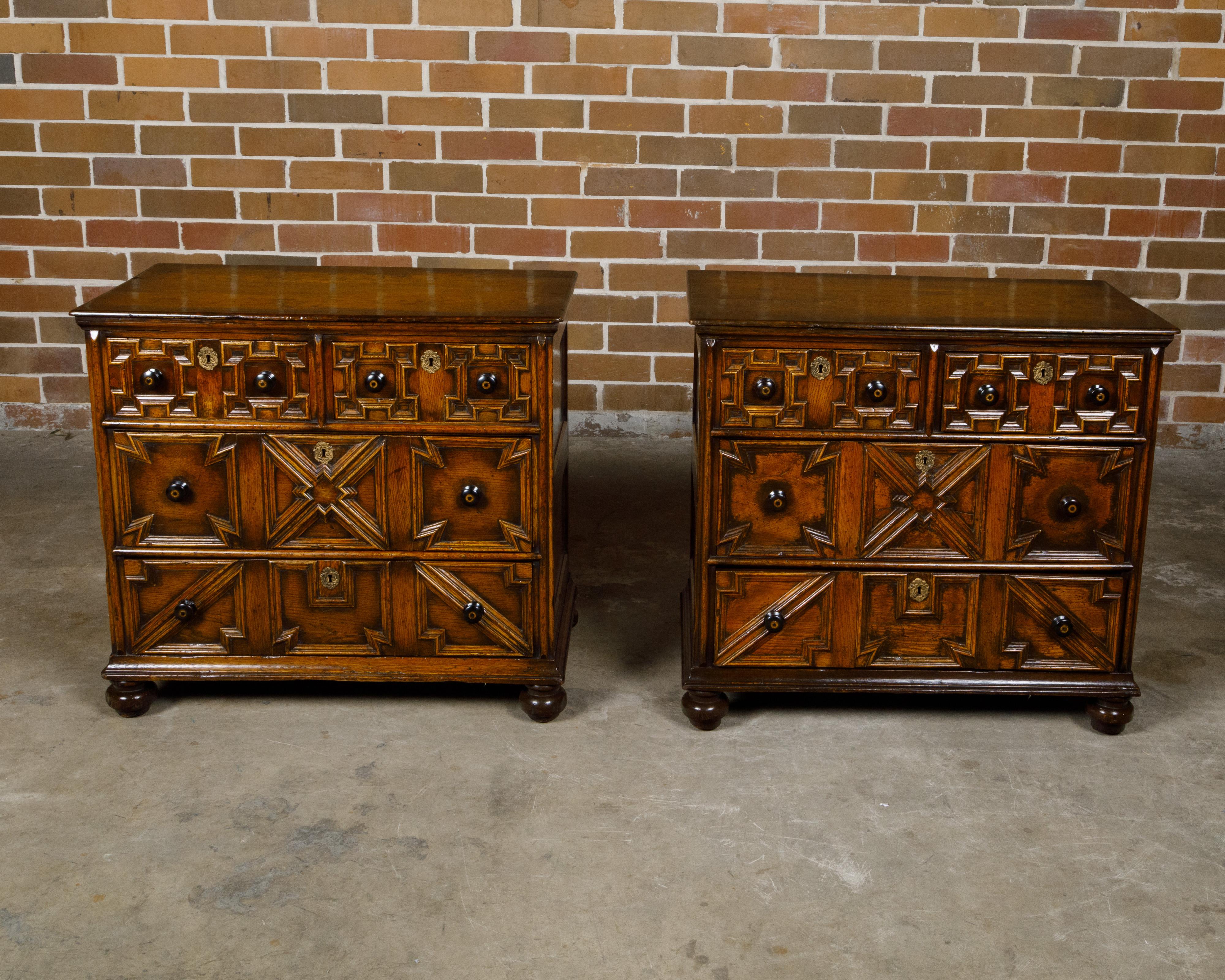 A pair of English oak geometric front four-drawer chests from the 19th century with ebonized pulls and turned feet. Created in England during the 19th century, this exquisite pair of oak chests features a handsome geometric façade, showcasing a