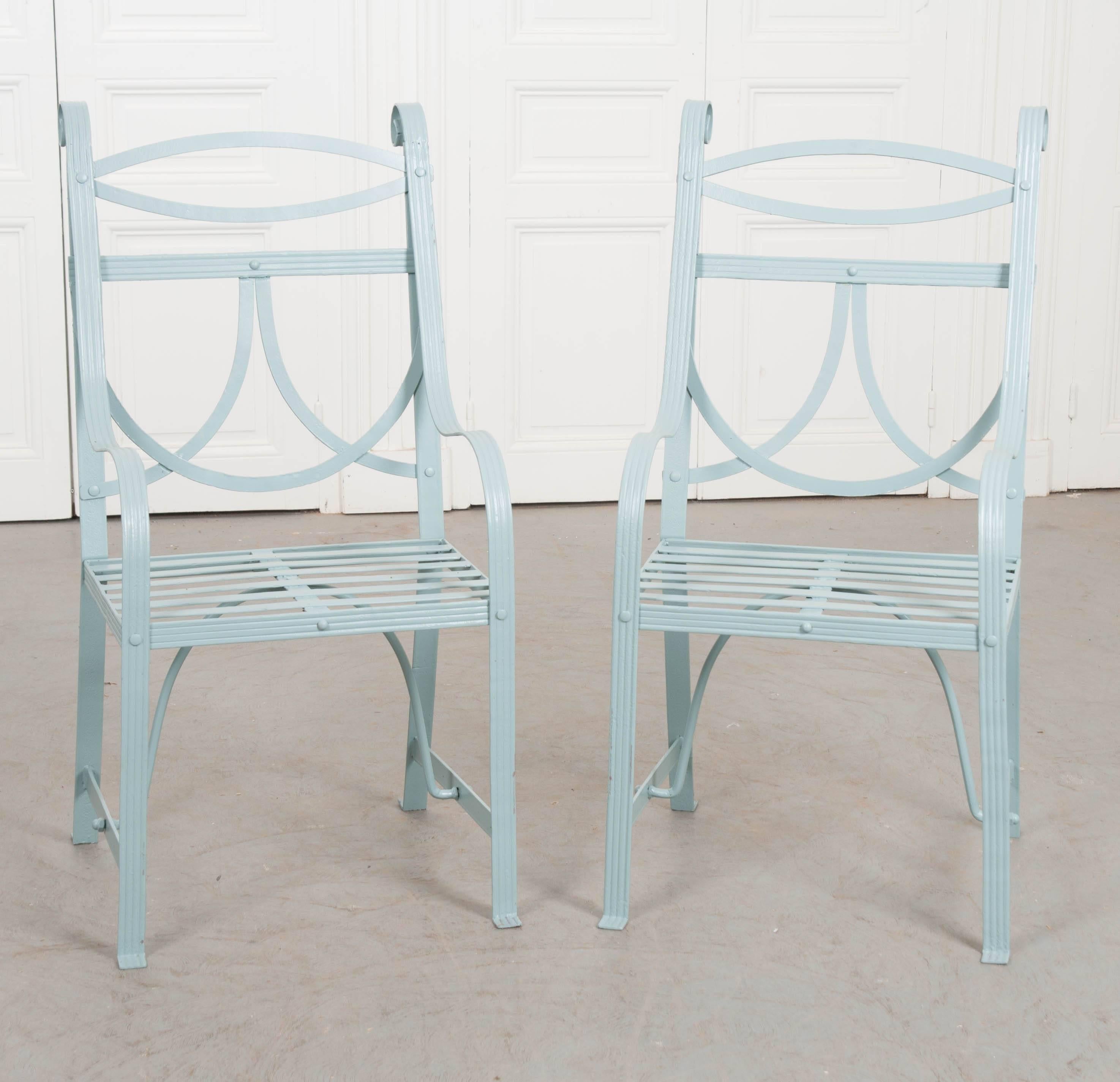 A fabulous pair of English Regency garden armchairs from the 19th century that have been recently painted. This recent coat of powder blue paint has these antique chairs looking fresh and new. The wrought iron set features a balance of curved and