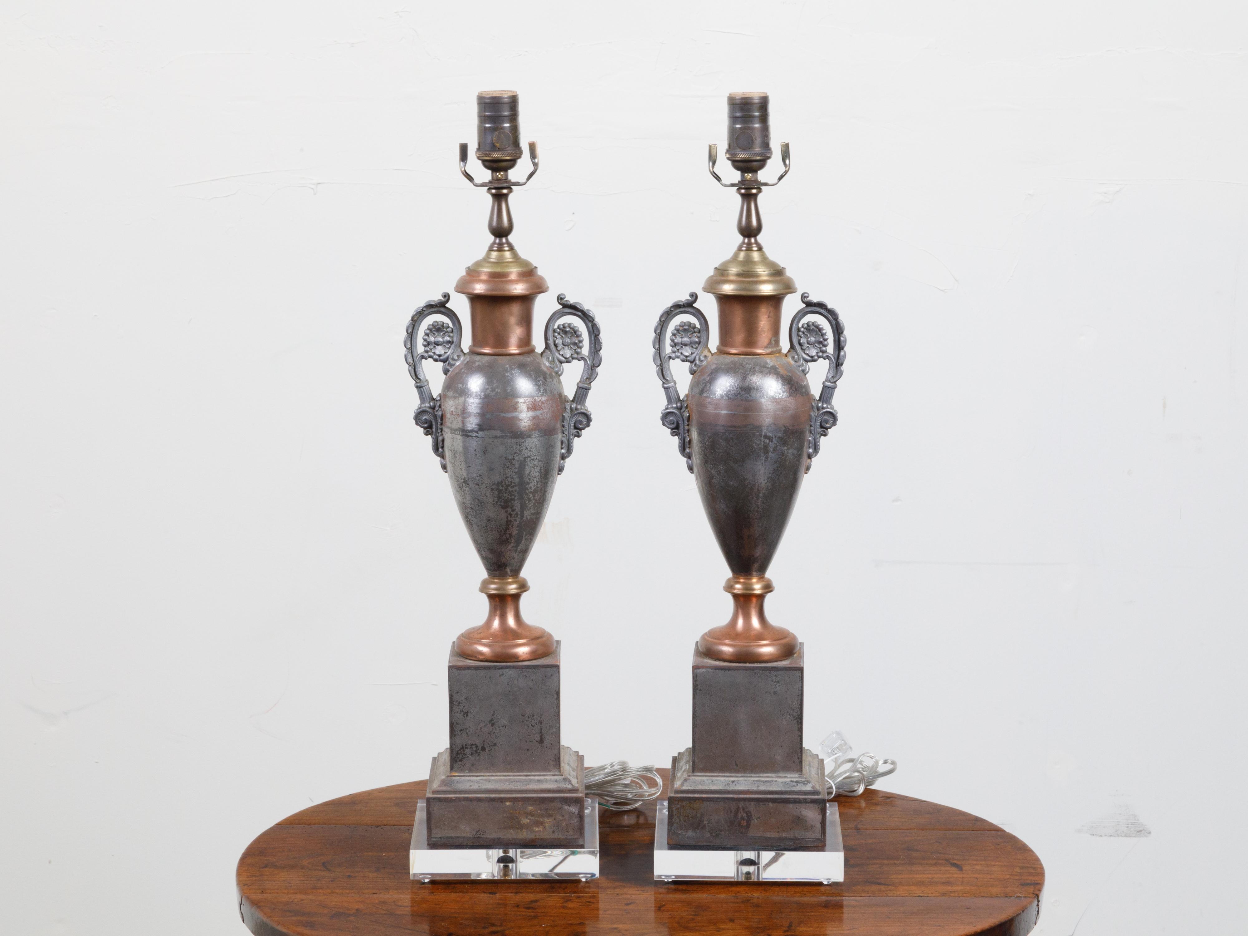 A pair of English tôle amphorae table lamps from the 19th century, with scrolling handles and lucite bases. Created in England during the 19th century, each of this pair of table lamps attracts our attention with its classical amphorae shape.