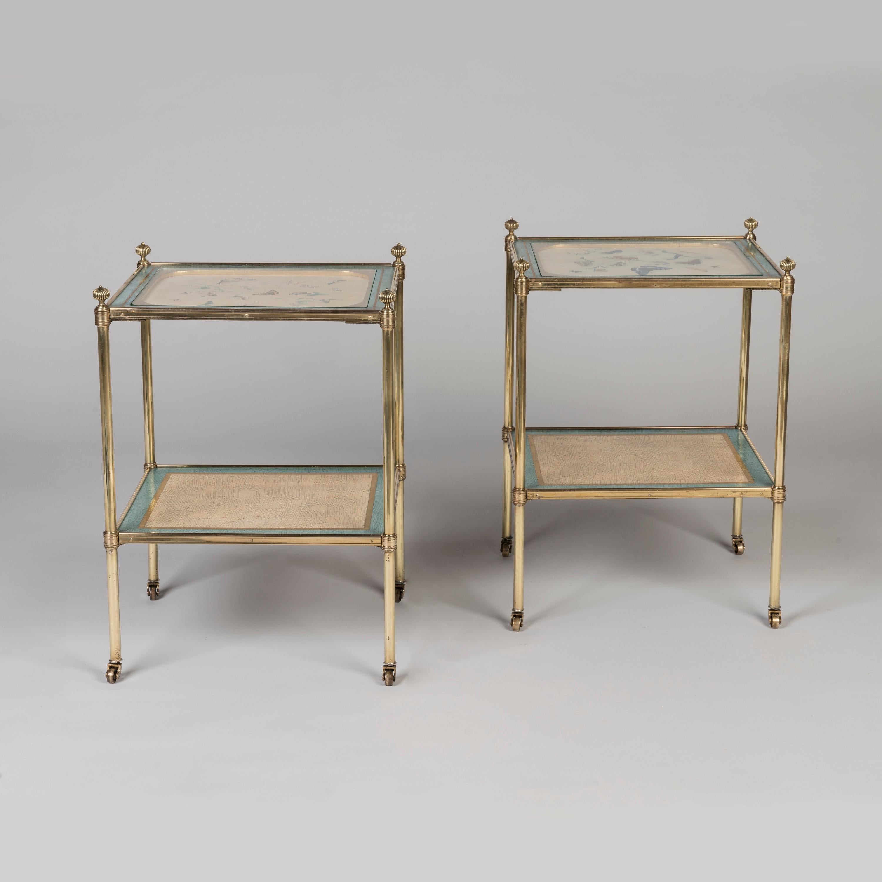 A Pair of Decorated Gilt Brass Étagère Tables

Of rectangular form, constructed in lacquered brass; the turned columns, with integral castors and capped by reeded finials, enclose two tiers with pale blue and parcel gilt edges, within channelled