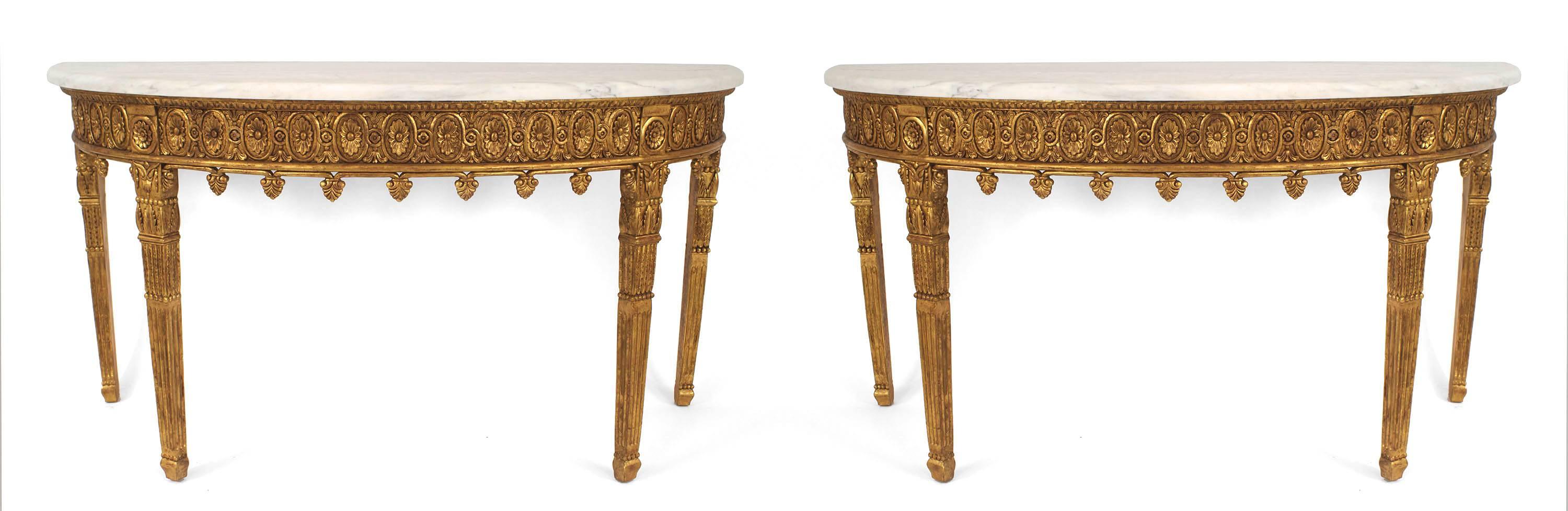 Pair of English Adam-style (20th Century) gilt carved demilune shaped console tables with finials on apron and fluted rectangular legs. (PRICED AS Pair).
 