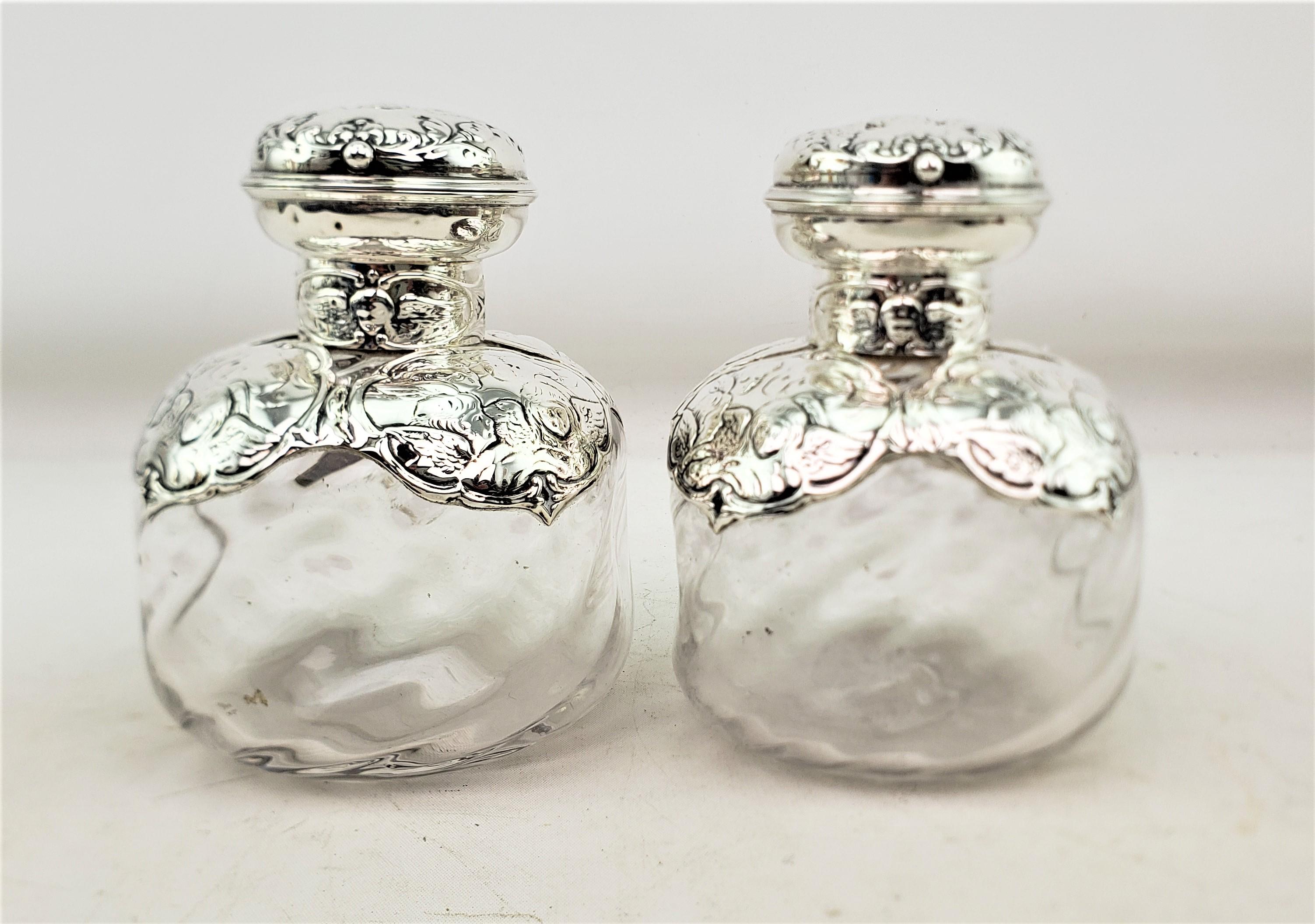 This large pair of antique perfume bottles was made by the well known silversmiths William Comyns & Sons Ltd. of England and date to approximately 1880 and done in the period Victorian style. The bottles are composed of clear glass with squared