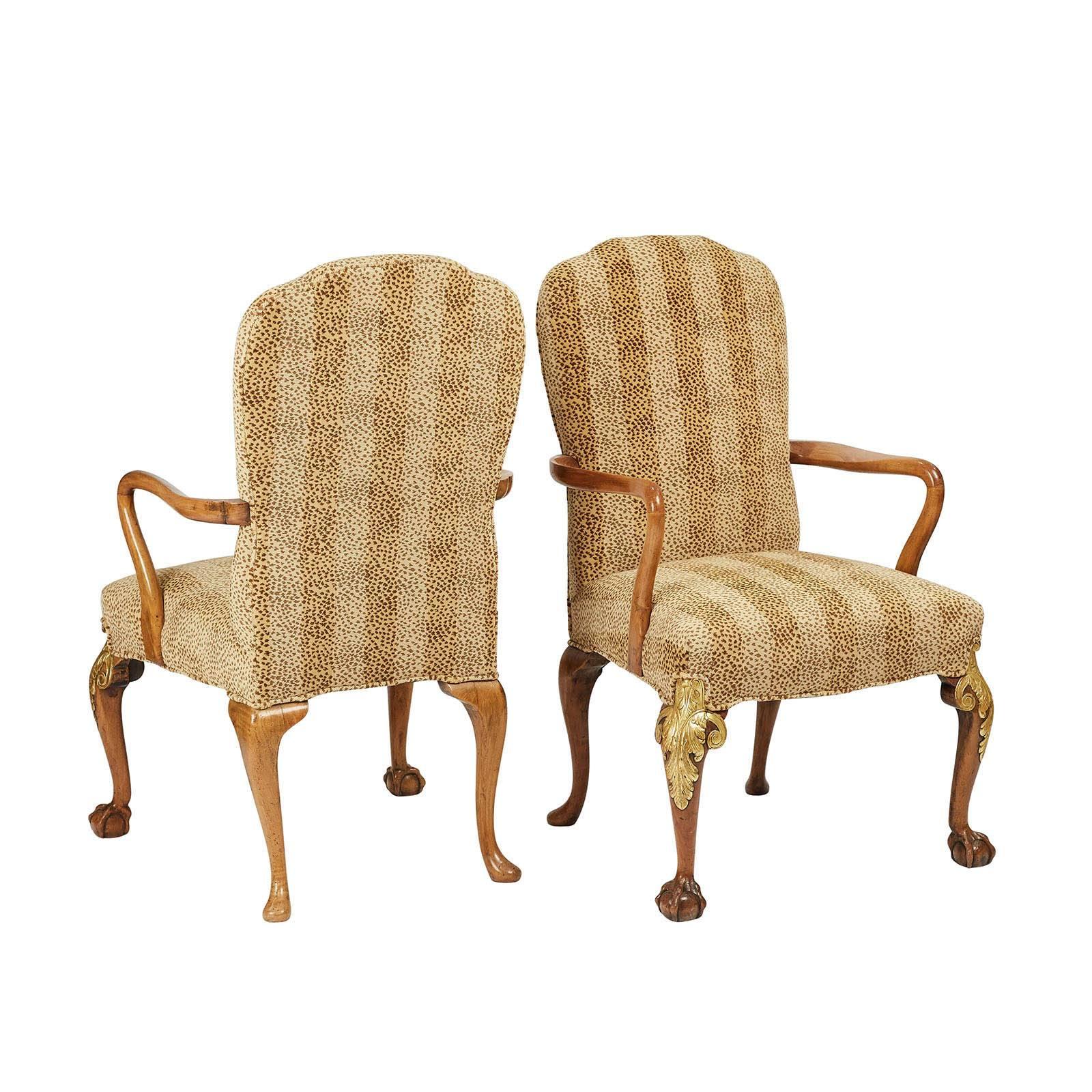 A pair of walnut armchairs in the George II style, with later gilding, circa 1890.

