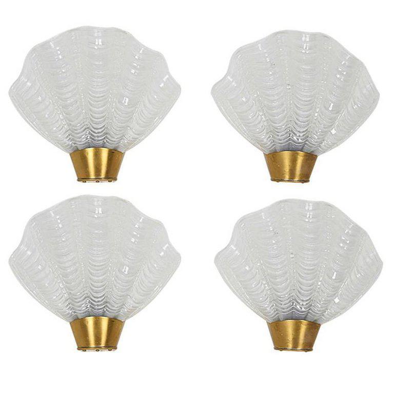 1930's Art Deco sconces with elegant shell design. The sconces are comprised of white hand molded frosted glass with fluted details and stylized ridges created in the form of sea shells. The sconces feature petite brushed brass metal fittings and