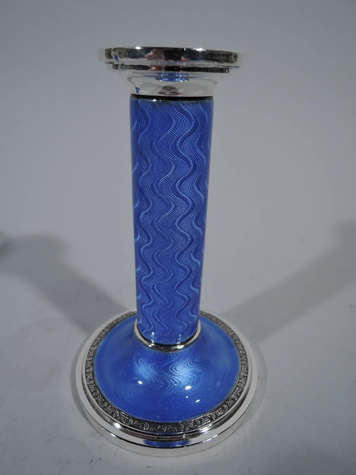 Pair of Art Deco sterling silver and enamel candlesticks. Made by Henry Matthews in Birmingham in 1930. Each: Column on domed foot. Blue guilloche enamel with wave pattern. Socket silver as is band at column base and foot rim with raised scrollwork.