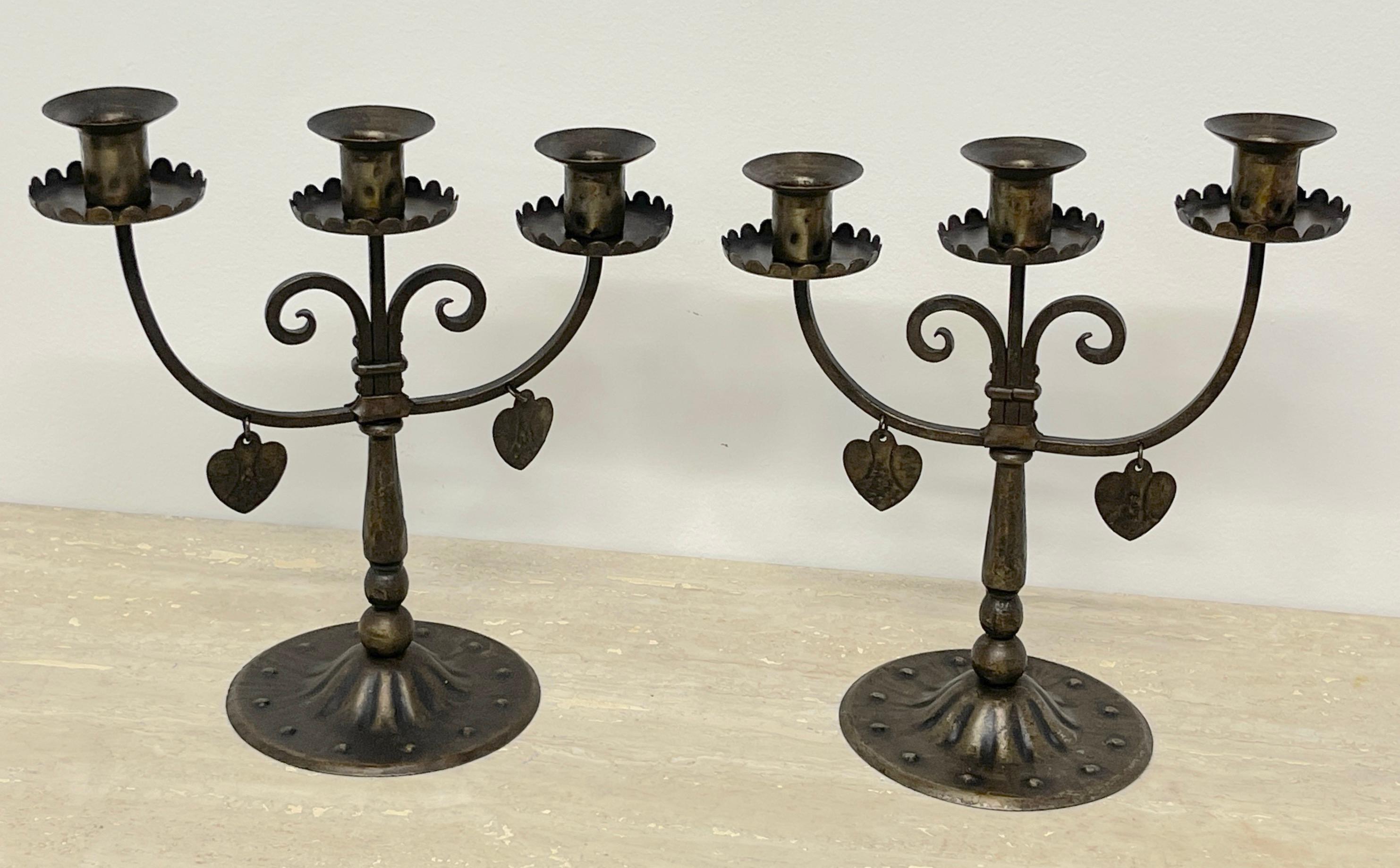 Pair of English Arts & Crafts Wrought Iron Three Candelabra with Hearts 
England, Early 20th century 

These English Arts & Crafts wrought iron three-candelabra with hearts are a stunning example of early 20th-century craftsmanship. Each candelabrum