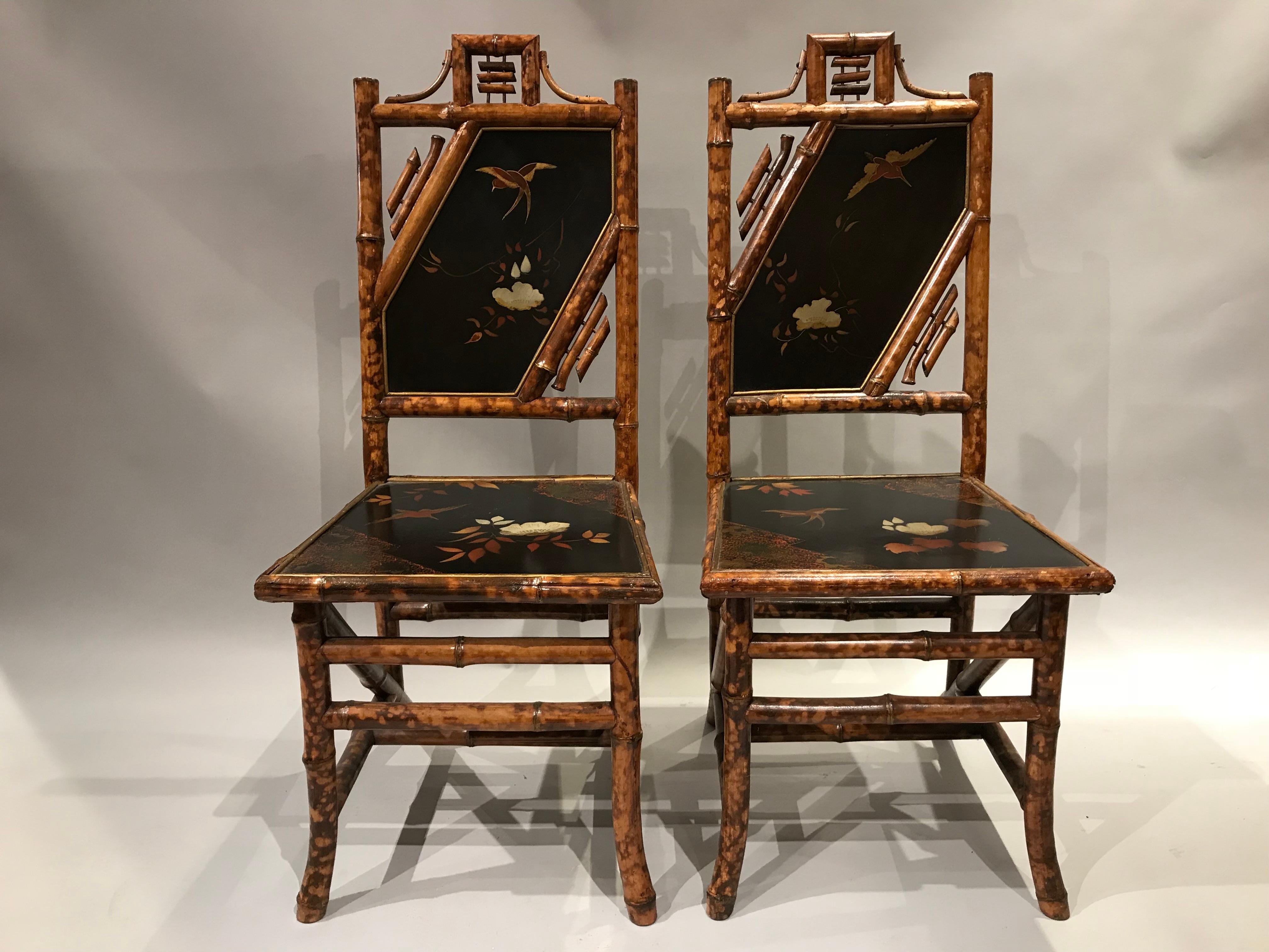 A fine pair of English bamboo side chairs with lacquered bird and foliate decorated seats and back panels, in very good condition, with minor imperfections and light expected wear from age and use. Dimensions: Each measure 39.5 in H x 16.5 in W x 19