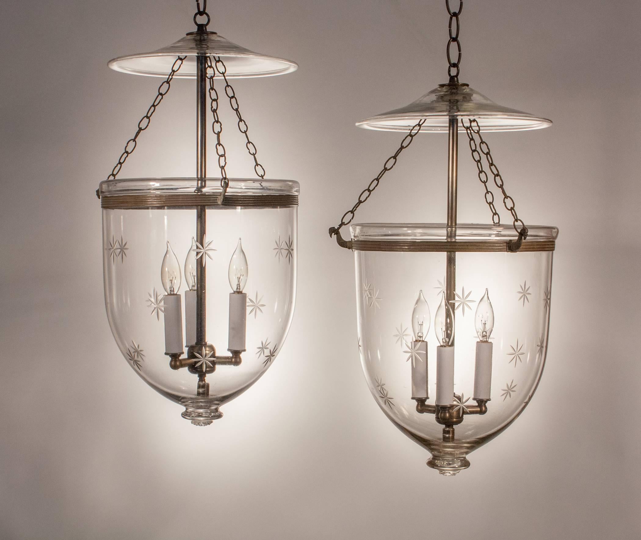 A wonderful pair of 19th century bell jar lanterns from England with authentic rolled brass bands and chains. These medium-sized hall lanterns are full in form and feature fine quality handblown glass, including desirable swirls and air bubbles. In