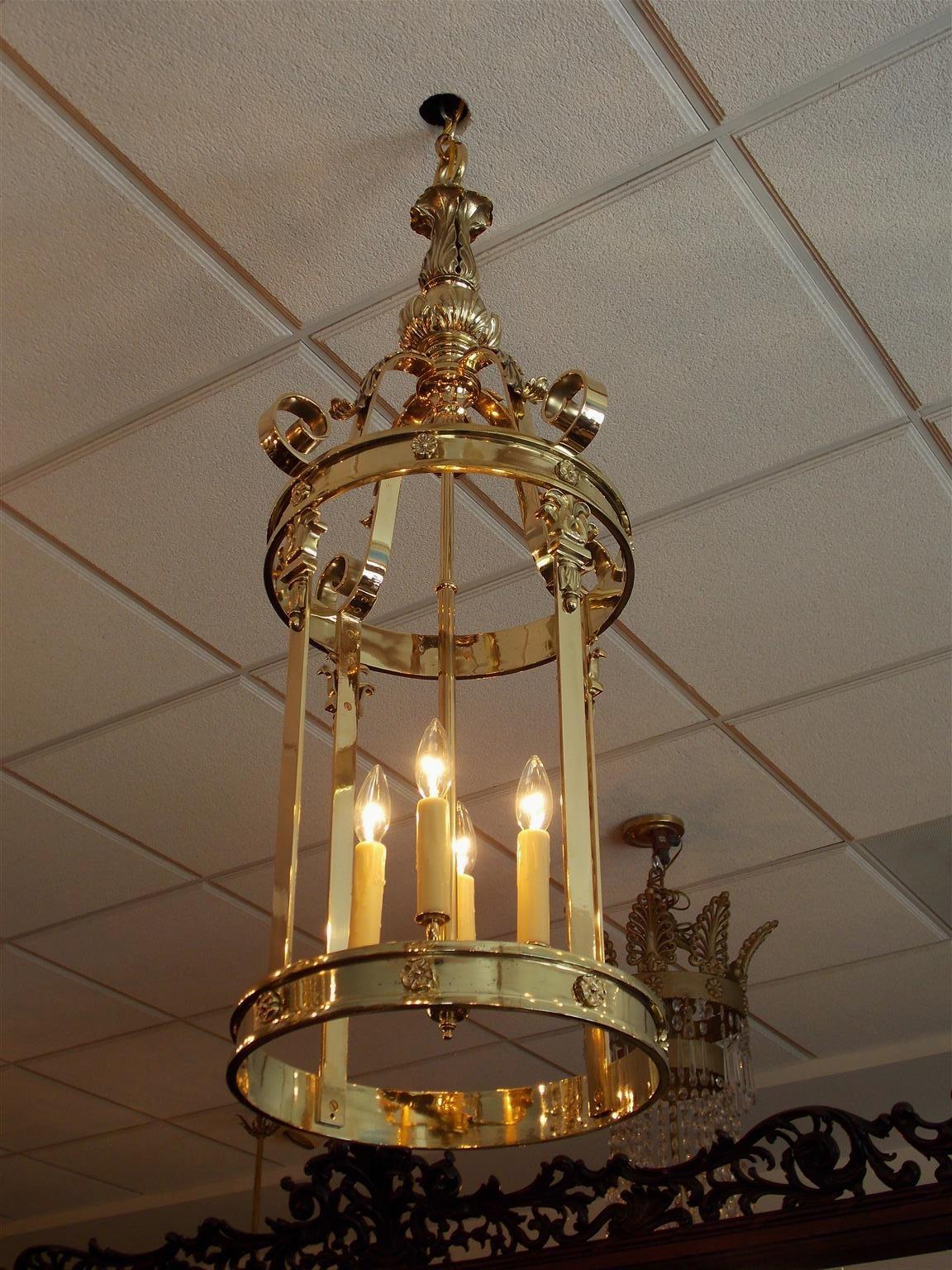 Pair of English brass acanthus foliage medallion hanging hall lanterns with decorative exterior scroll work, and fitted with an interior four light cluster, Early 19th century. Pair were originally candle powered and have been electrified.