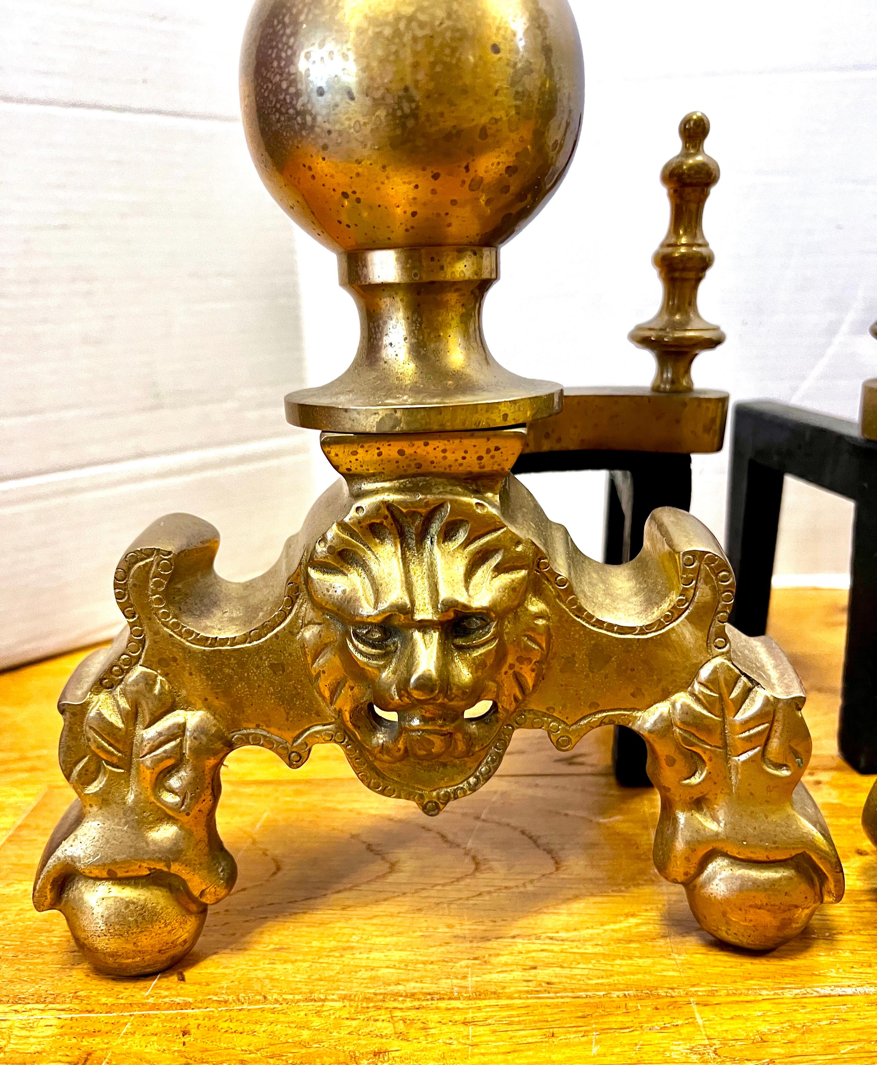 Stunning pair of luxurious heavy brass cannonball andirons with intricate lion head details.