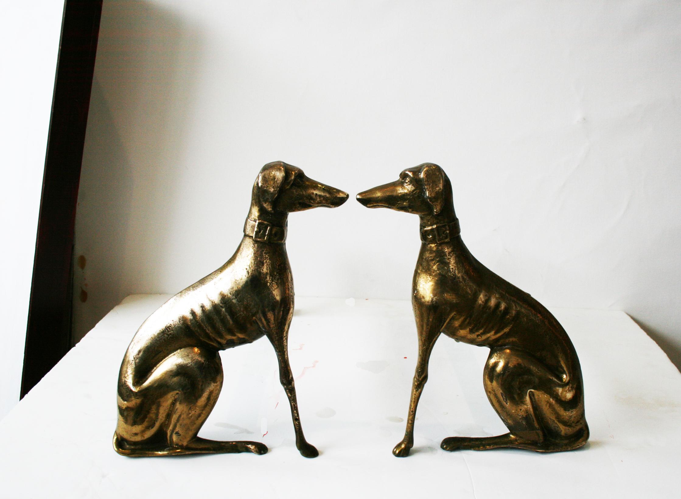 A pair of English brass greyhound dog andirons from the first half of the 20th century. This pair of brass andirons features two greyhounds facing each other. Their facial expressions along with the details of their bodies are skillfully