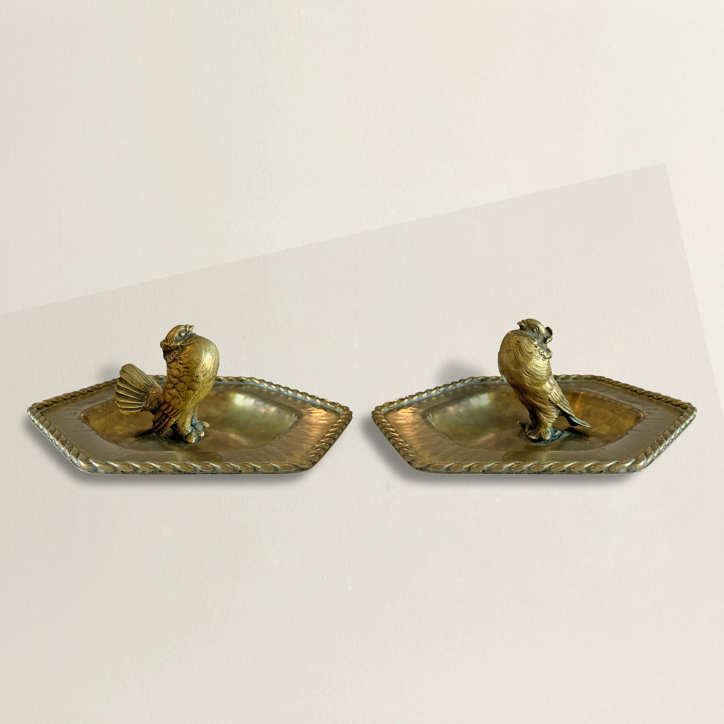 A charming pair of early 20th century English brass pigeon catchalls, one with a puffed-up male pigeon courting the female pigeon on the other. These are perfect for catching the keys or coins on your entry table, or filled with anything else you're
