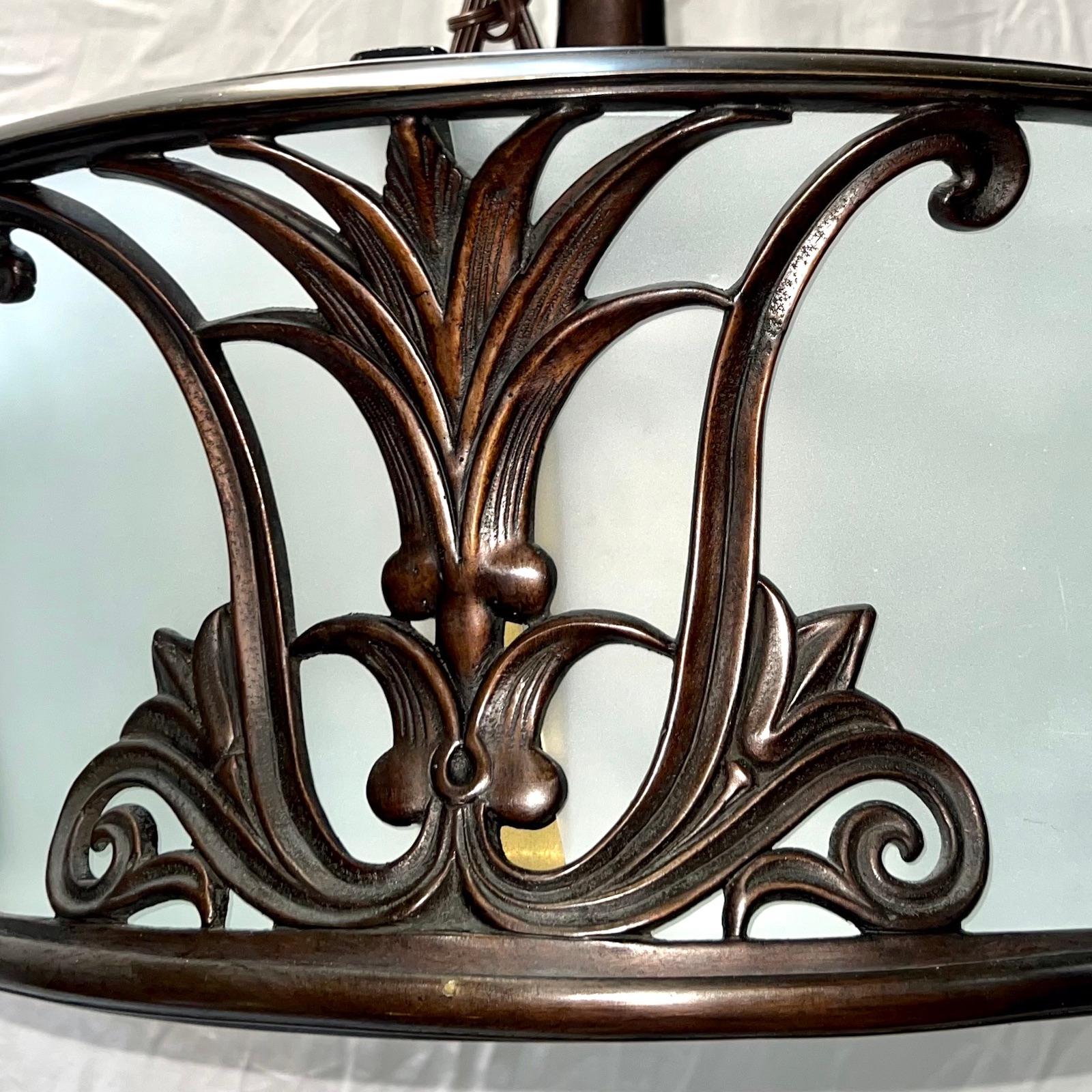 Pair of circa 1920's English bronze light fixtures with frosted glass insets and eight interior lights. Sold individually.
 
Measurements:
Drop: 26
