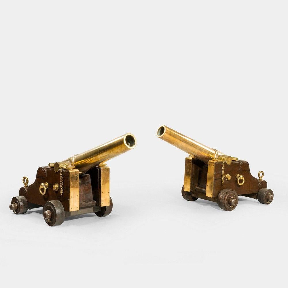 A fine pair of English bronze signal cannon, the tapering 36 inch two stage barrels set upon original mahogany carriages with bronze fittings and bronze sheathed front cheeks.