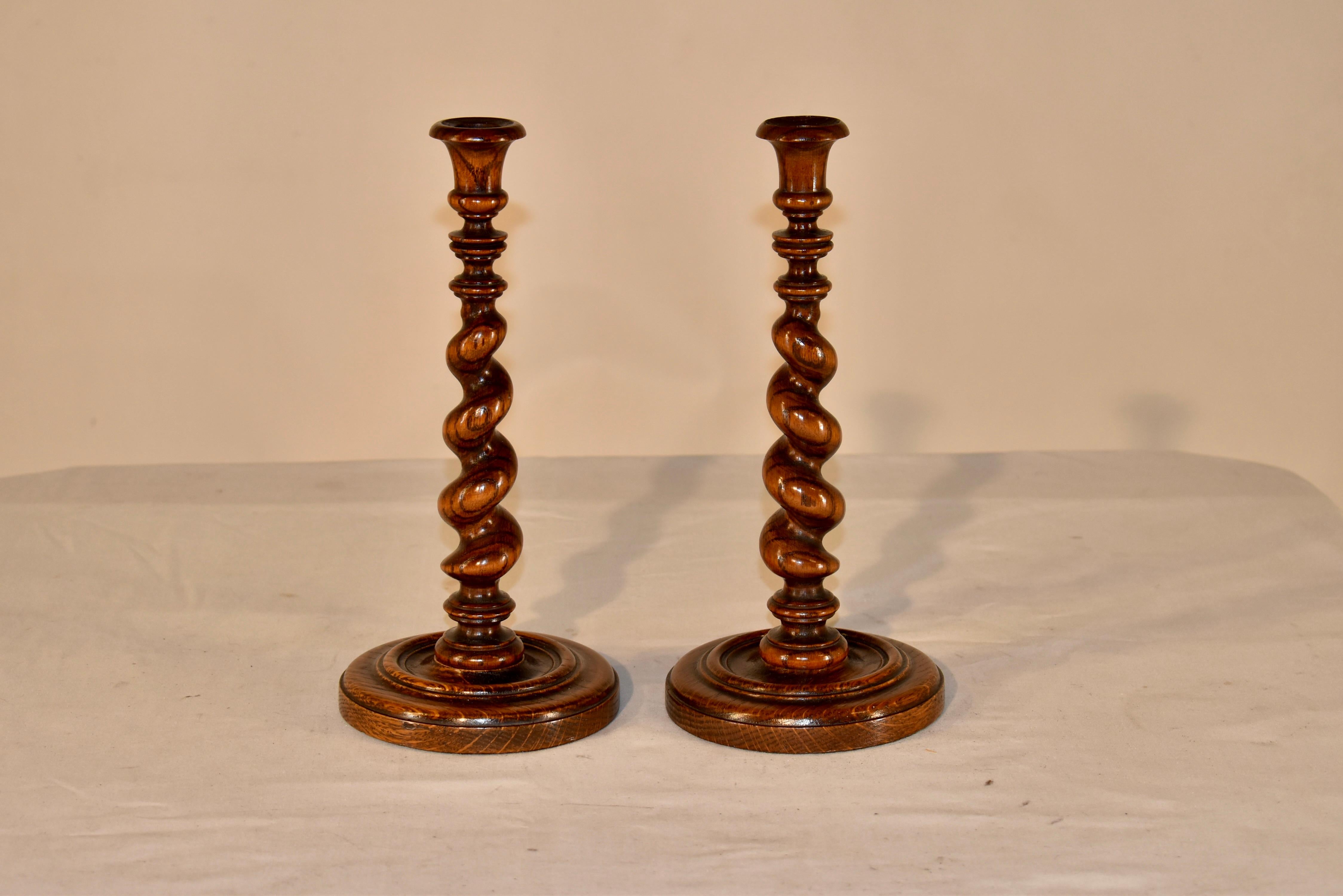 Coppia di candelieri in quercia del XIX secolo provenienti dall'Inghilterra.  Le coppe delle candele sono ben accordate e poggiano su deliziosi collari torniti e steli d'orzo graduati sapientemente torniti, sostenuti da basi tornite a mano.  Sono