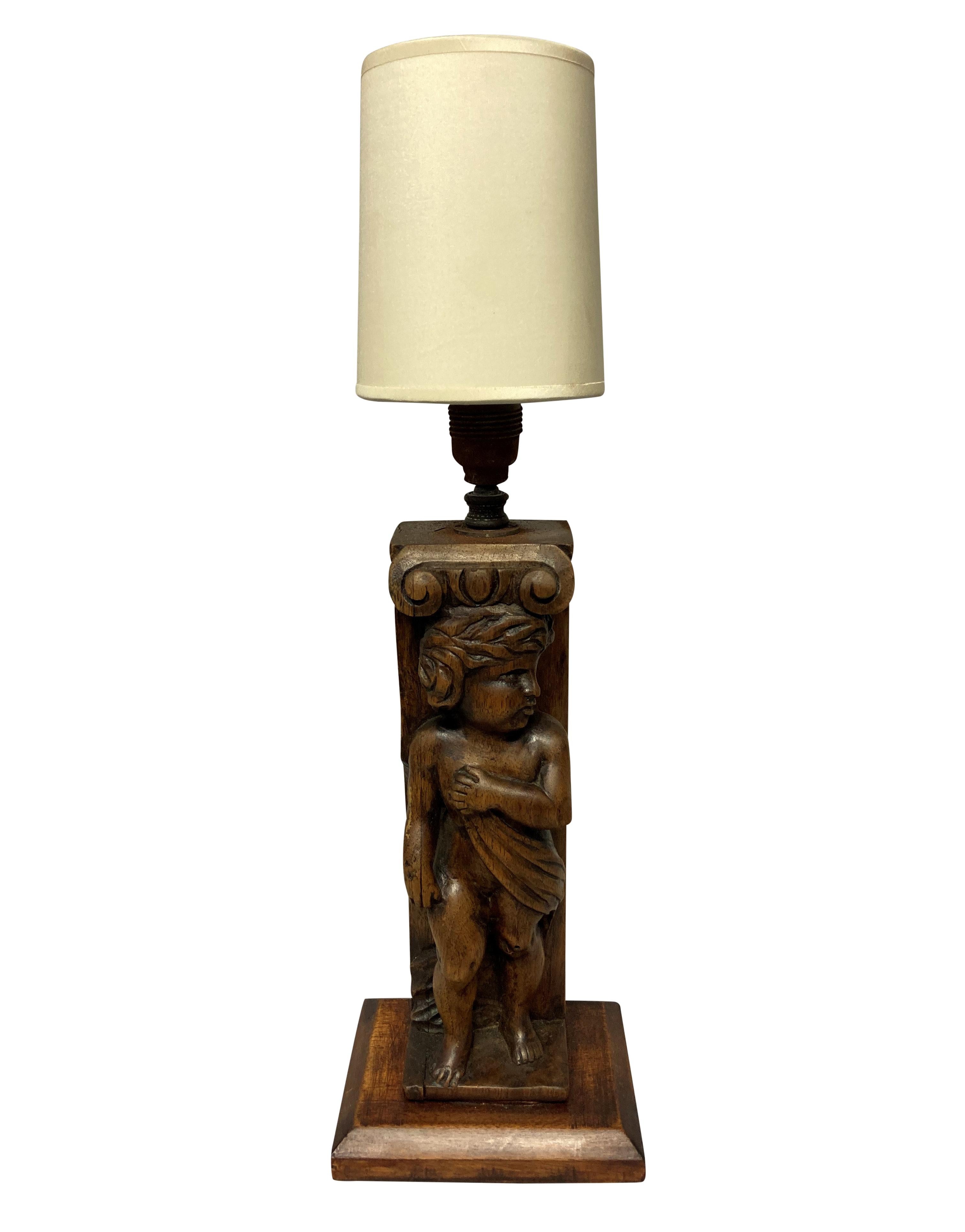 A pair of carved walnut English lamps in the Medieval manner depicting cherubs.