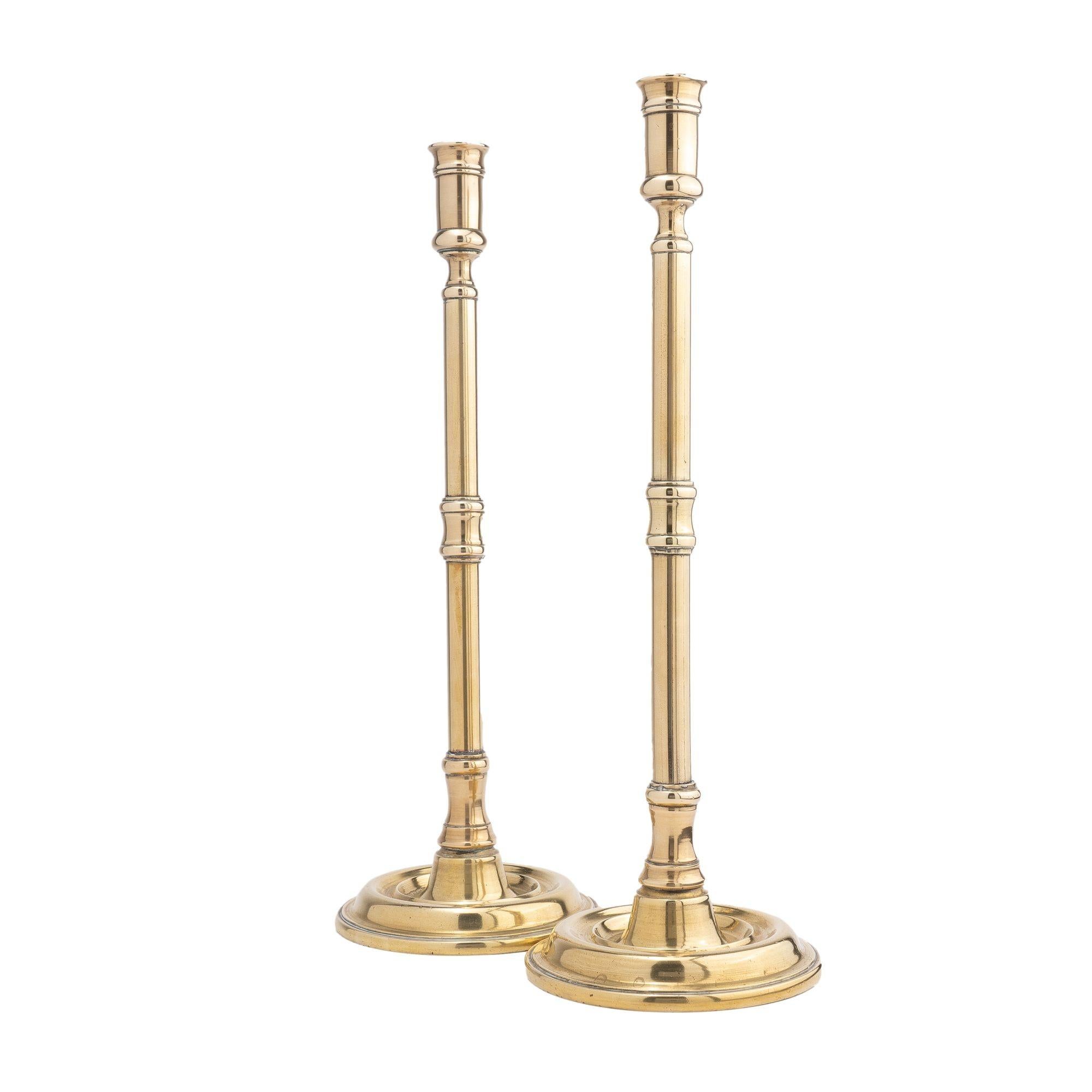 Pair of English tavern candlesticks, with an elongated candle cup on a tubular shaft. The shaft is interrupted by a beaded edge, concave molding, repeated at the base joining the circular dished base and peened to the shaft. One candlestick is