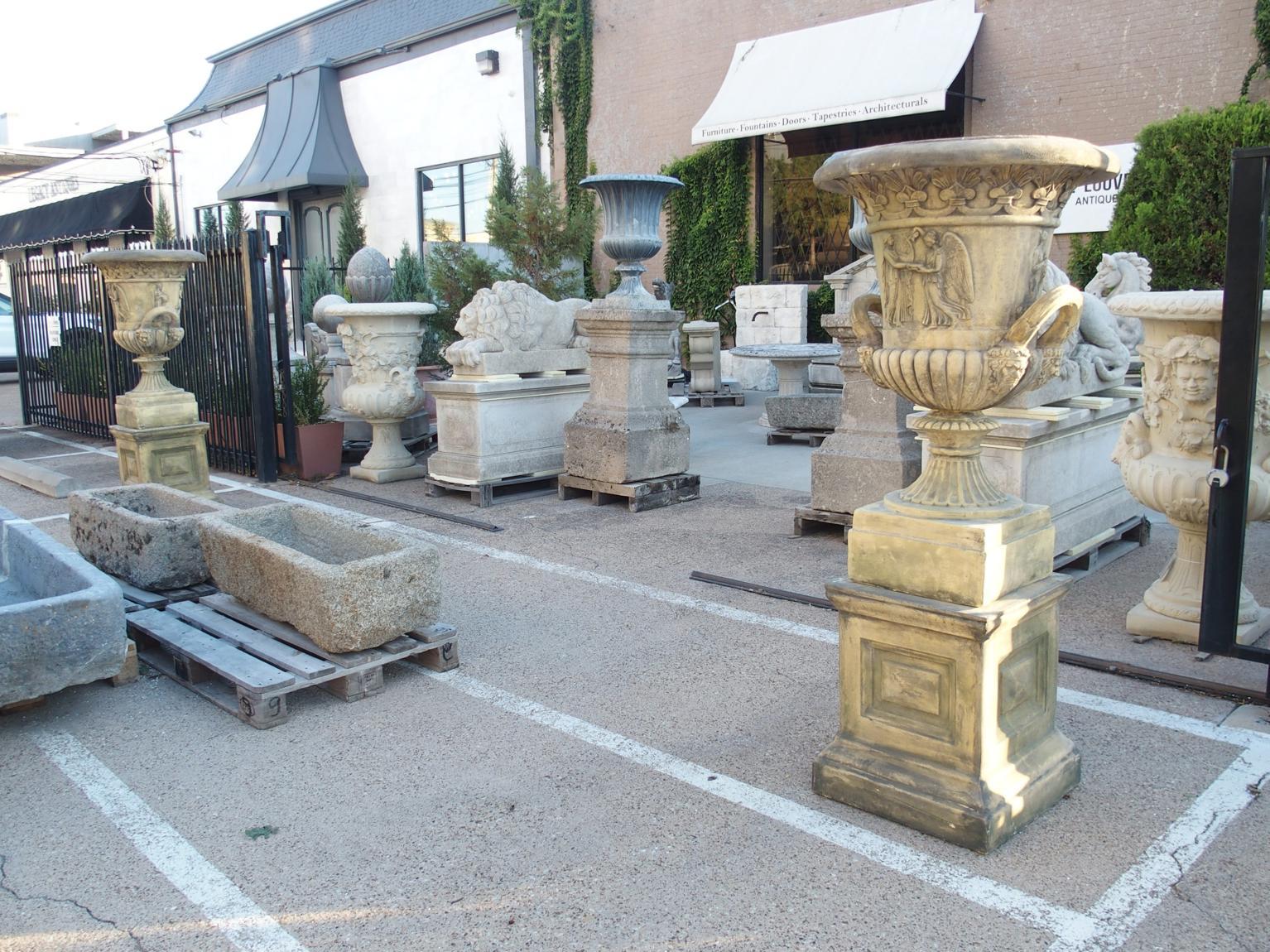 This pair of English garden urns has a very appealing ochre and gray hue, making them attractive garden ornaments. The Neoclassical-style urns, which have been cast in two sections, are supported by a rectilinear plinth. Each side of the plinth has