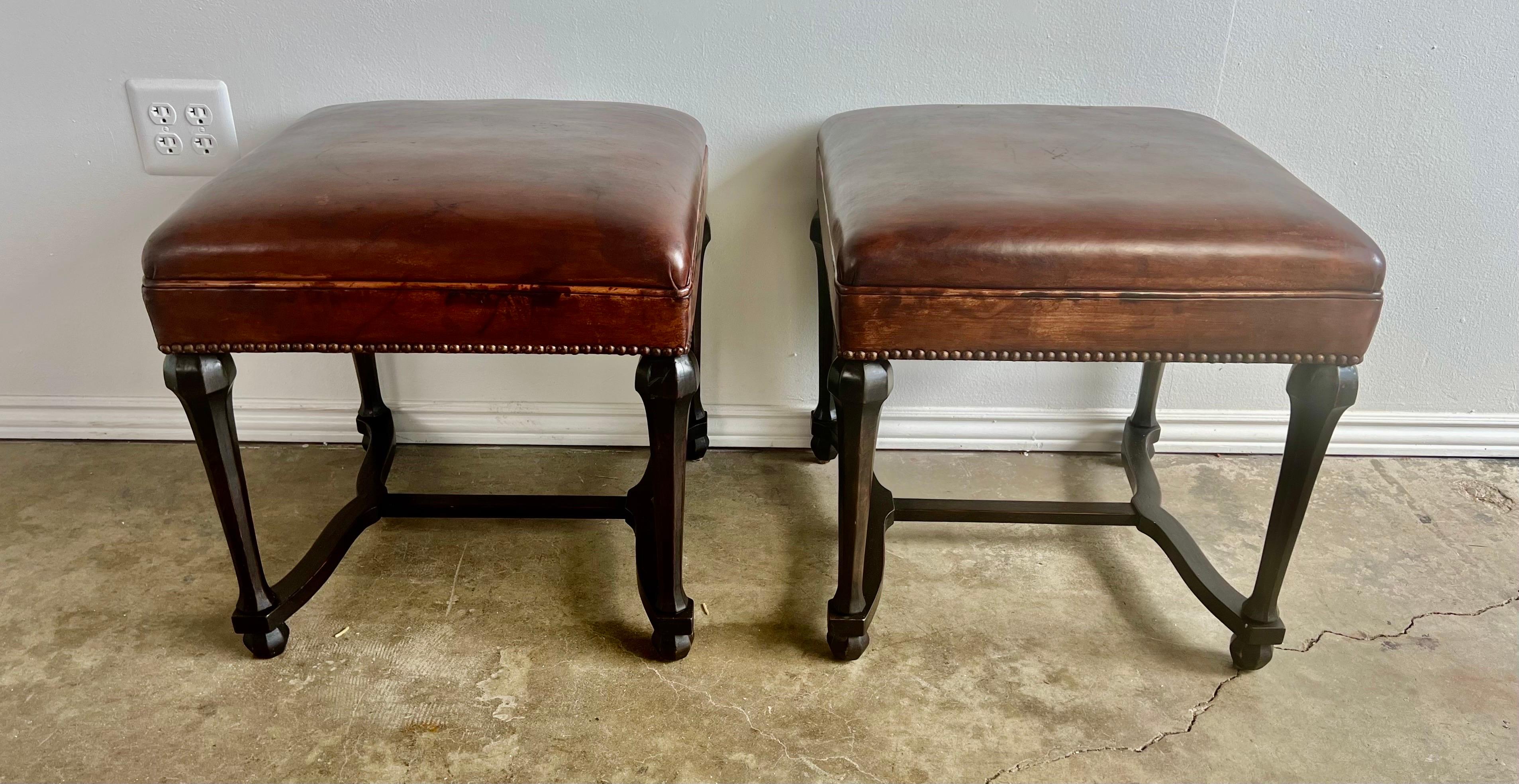 Pair of 19th century English Charles II Style walnut benches with the original leather upholstered seats. Detailed with antique nailhead trim. Soft wear consistent with age and use of benches. The leather has developed a beautiful patina over the