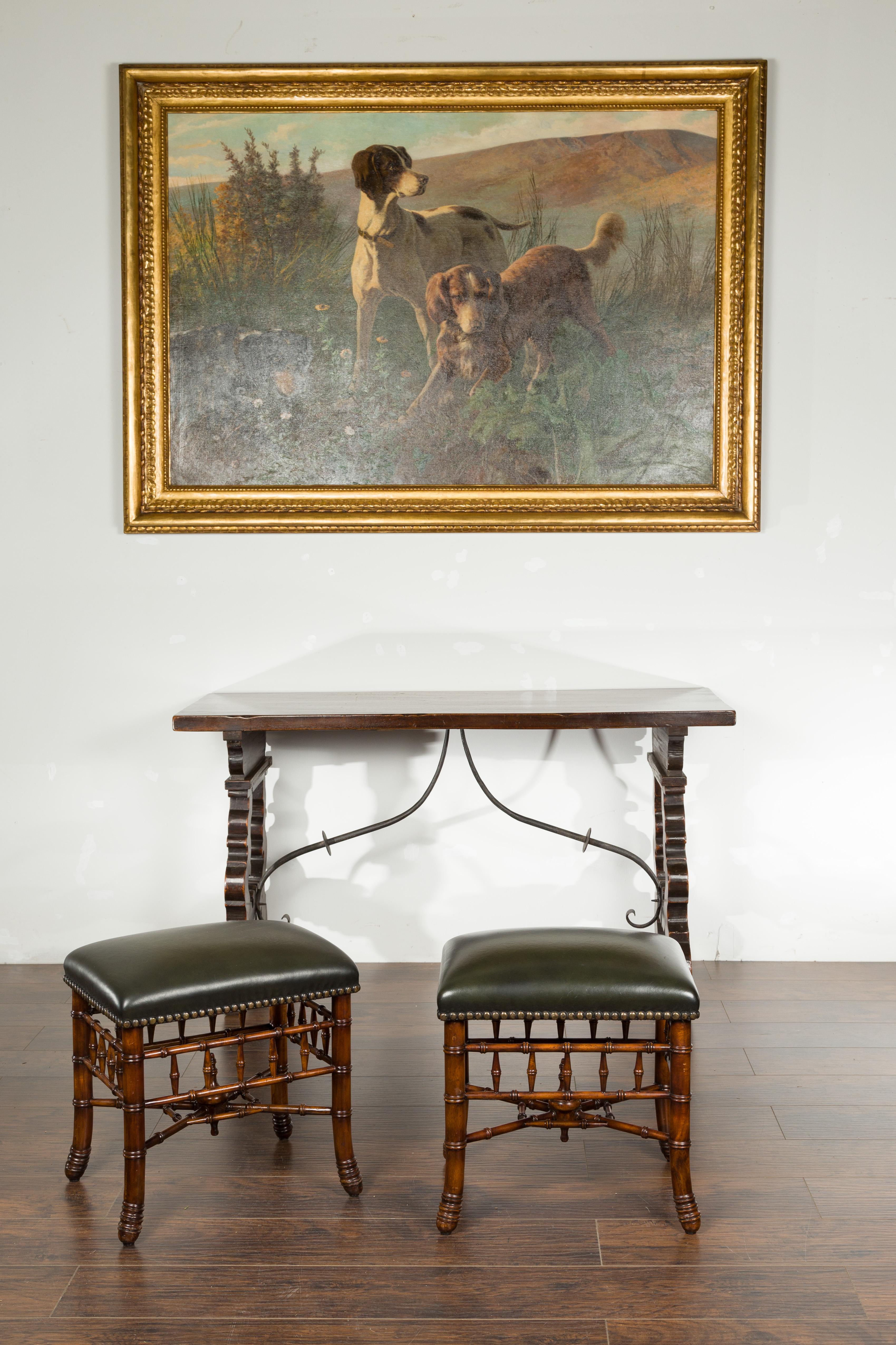A pair of English Chinese Chippendale style walnut faux bamboo stools from the mid 20th century, with leather tops. Created in England during the midcentury period, each of this pair of stools features a rectangular leather top with brass nailhead