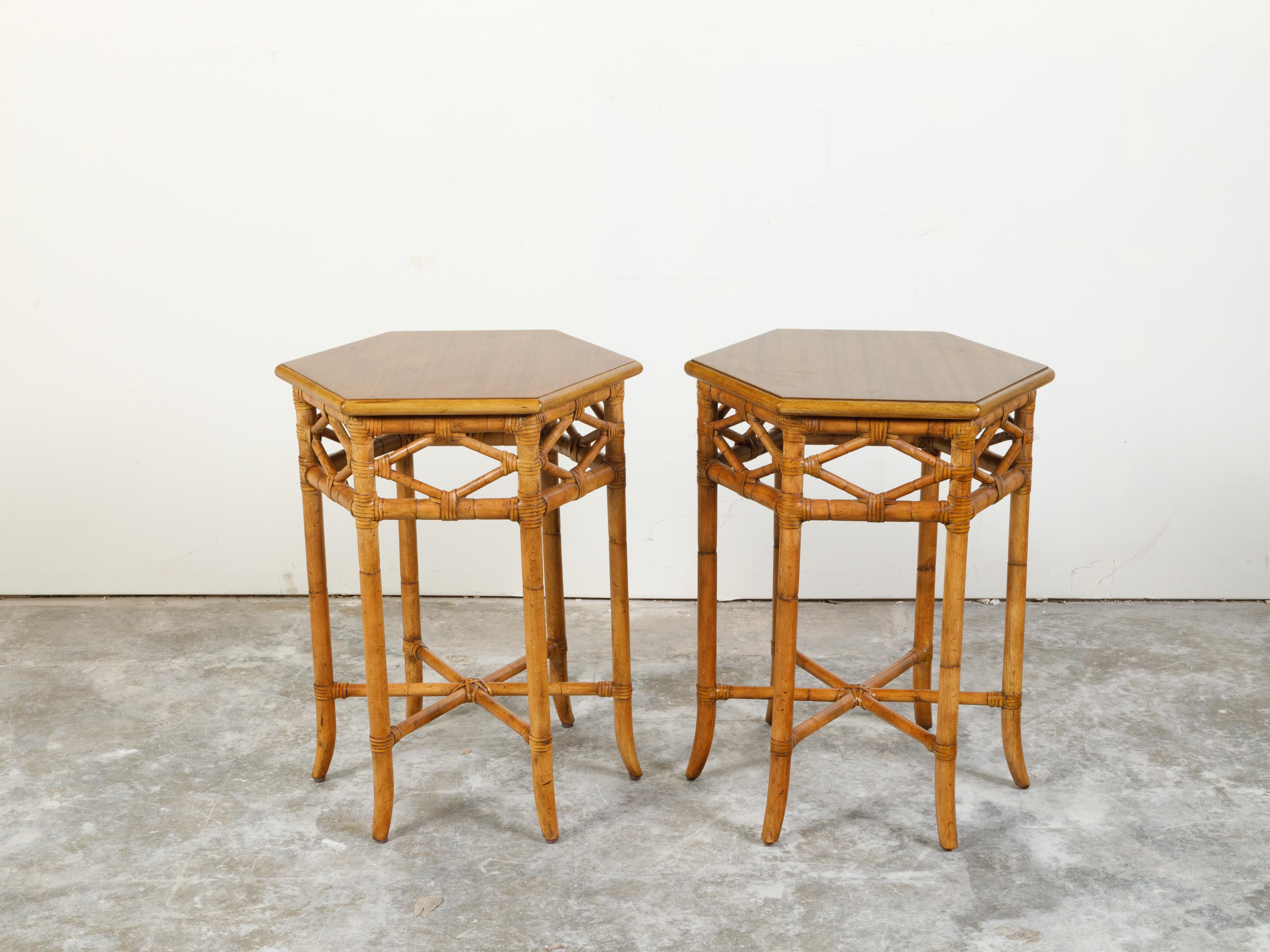 A pair of English Chinoiserie style faux bamboo side tables from the mid 20th century, with hexagonal tops and star-shaped cross stretchers. Created in England during the midcentury period, each of this pair of side tables features an hexagonal top