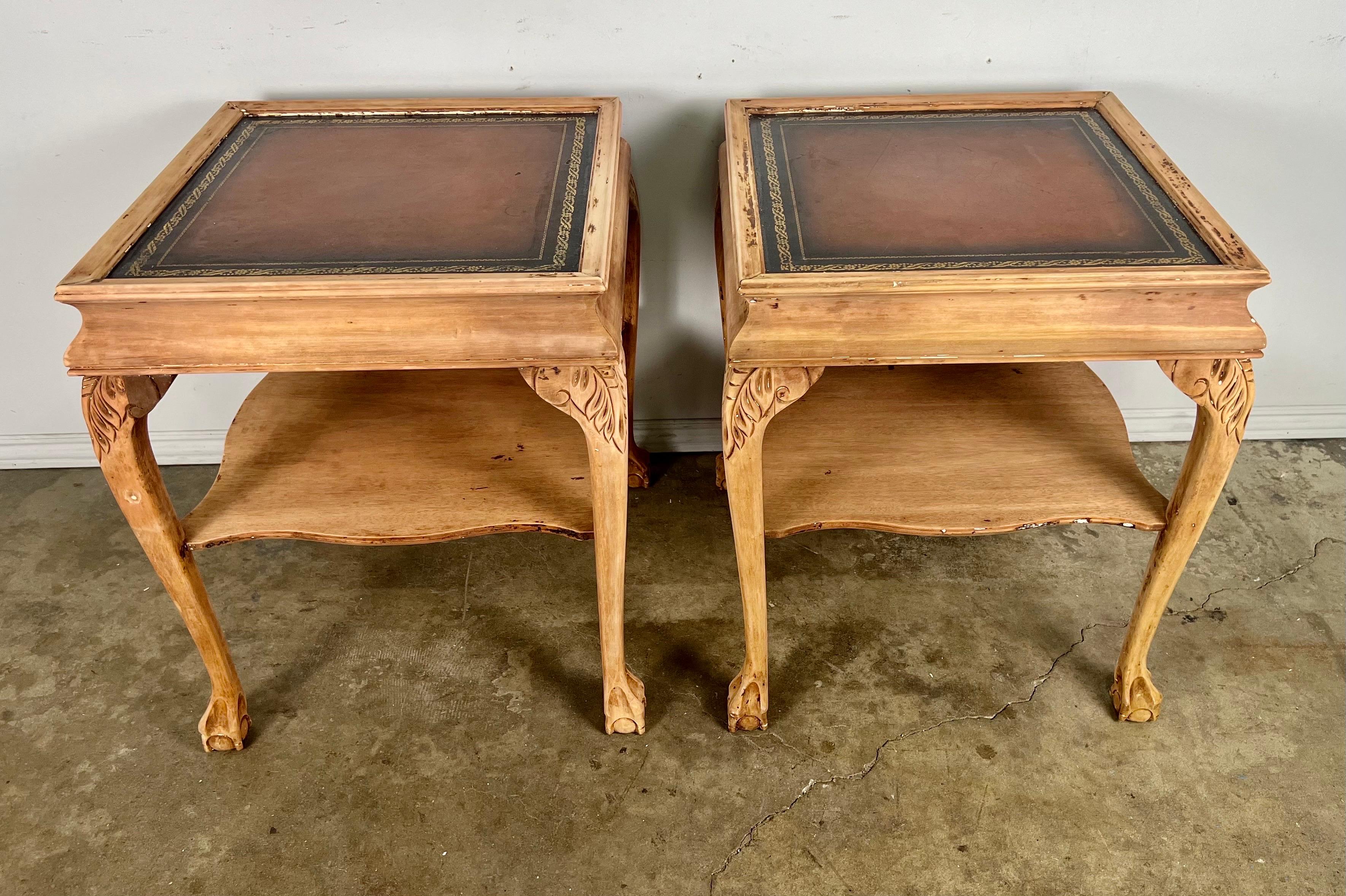 Pair of English Chippendale style bleached mahogany side tables. The tables have rich colored finely gold embossed leather tops. The tables stand on four legs that end in beautifully carved ball & claw feet. The legs are connected by a bottom