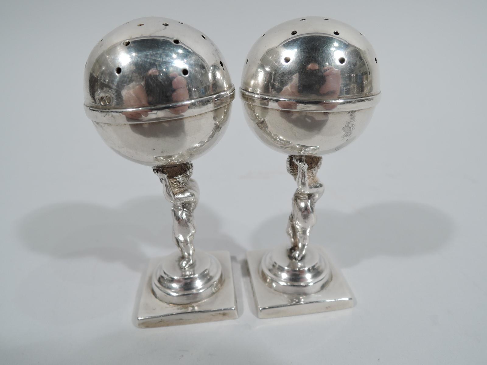 Pair of Victorian sterling silver salt & pepper shakers. Made by Stokes & Ireland in Birmingham in 1889. Each: A pierced globe is supported by a chubby, contrapposto cherub with wispy drapery and bare bottom, who strains under the weight (of the