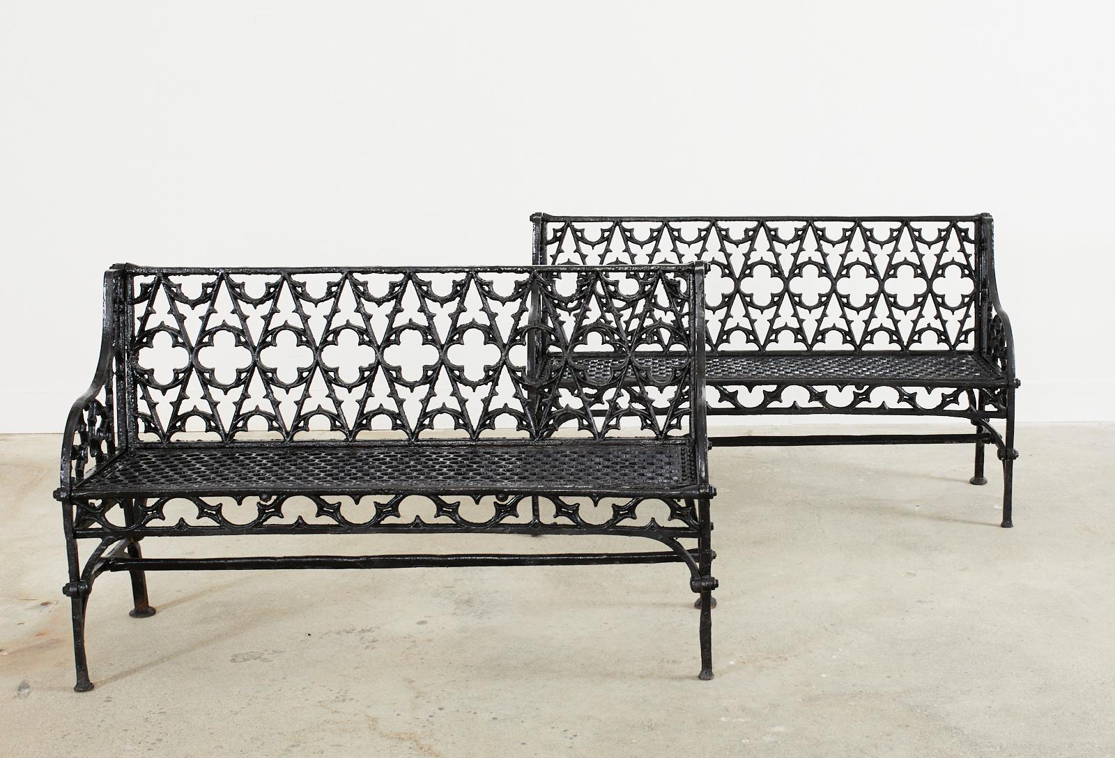 English Coalbrookdale foundry attributed cast iron garden benches. Made in the Gothic Revival English taste featuring Gothic tracery backrest centered by quatrefoil designs. The gracefully curved arms enclosing demilune motif patterns. The seat has