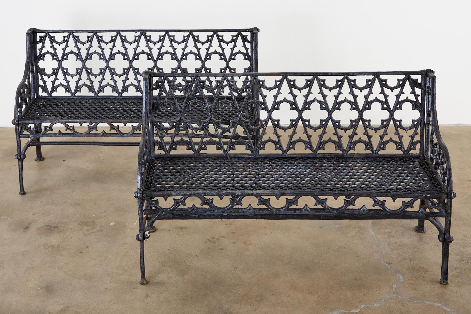 English Coalbrookdale foundry attributed cast iron garden benches. Made in the Gothic Revival English taste featuring Gothic tracery backrest centered by quatrefoil designs. The gracefully curved arms enclosing demilune motif patterns. The seat has