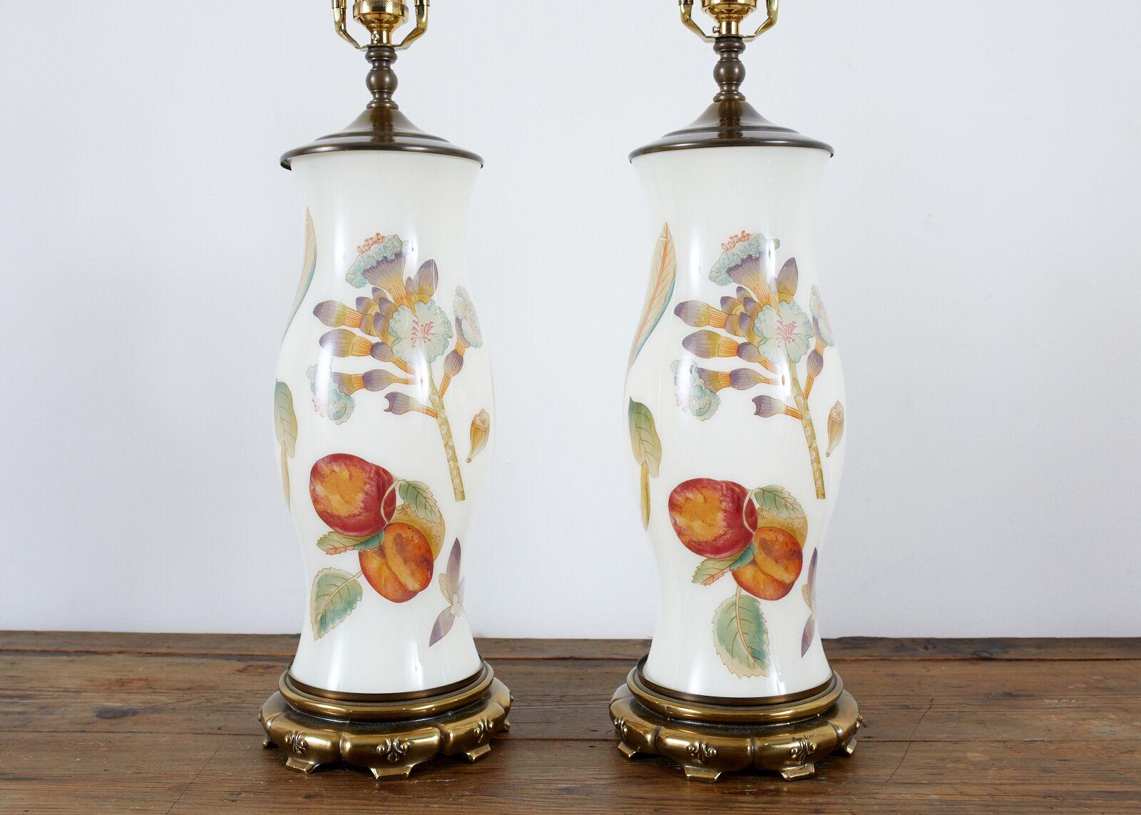 Stunning pair of English decalcomania vase table lamps decorated in the Hollywood Regency taste. Featuring baluster form glass vases with images of peaches, pineapples, palm leaves, and flowers. The vases are mounted to Asian Style brass bases in