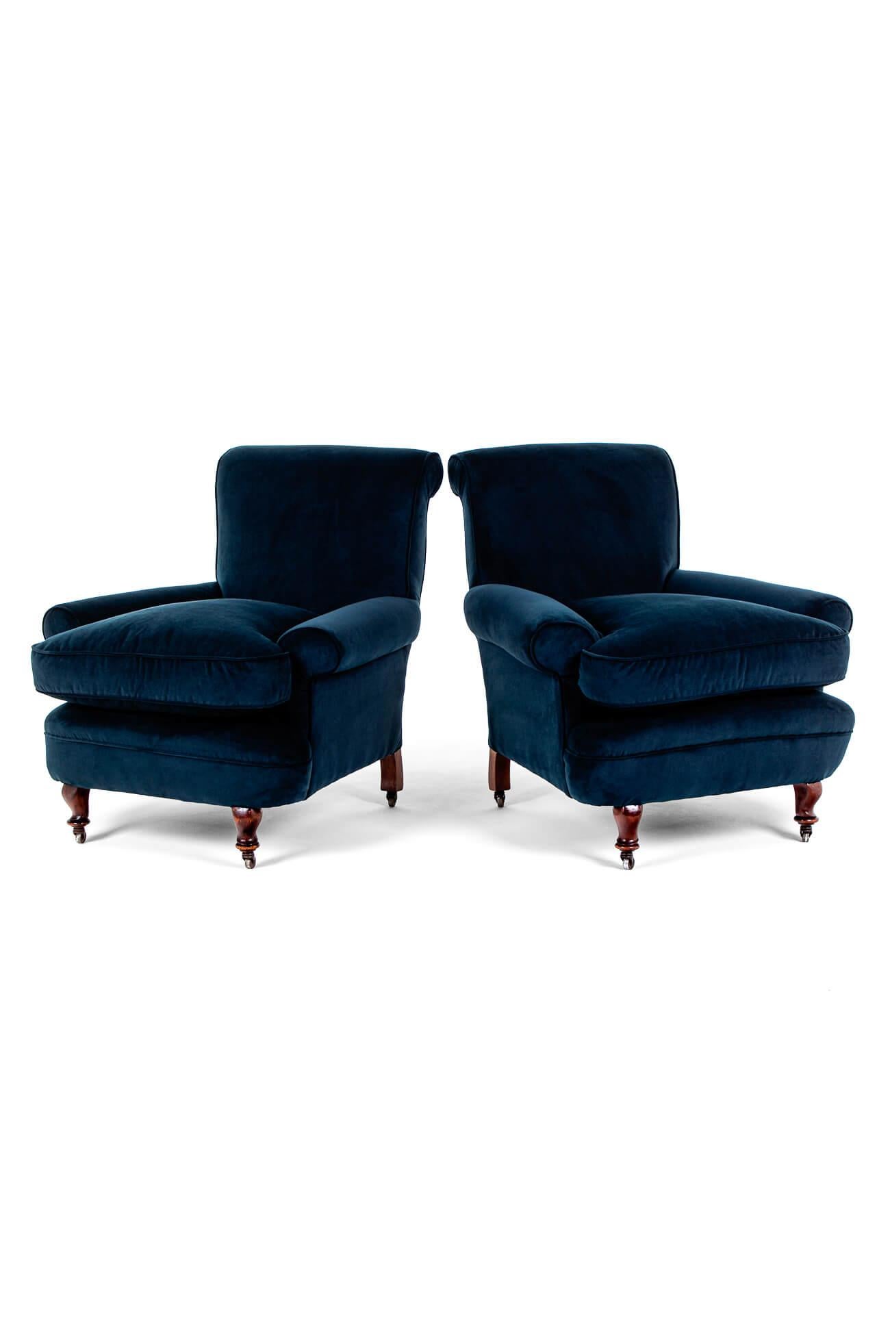 Maravillosa pareja de sillones azul marino de generosas proporciones, con asientos profundos y acogedores.

Con respaldos altos y brazos con volutas en los anchos marcos de caoba.

Con patas delanteras torneadas levantadas sobre ruedas originales de