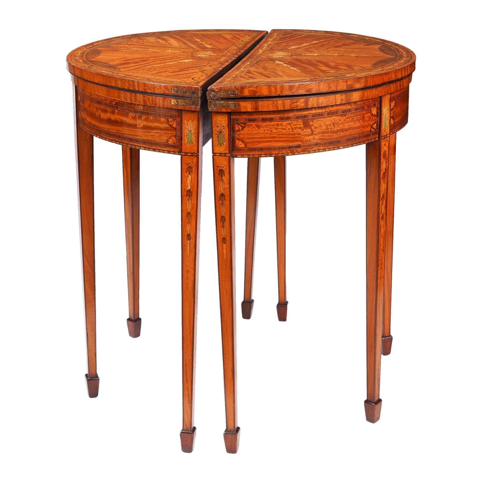 Pair of English Edwardian flip top demilune tables with marquetry inlay in the Sheraton taste on the top leaf, apron, dies and legs. The top is veneered with five radiating book matched satinwood panels from a floral inlaid demilune. The cross