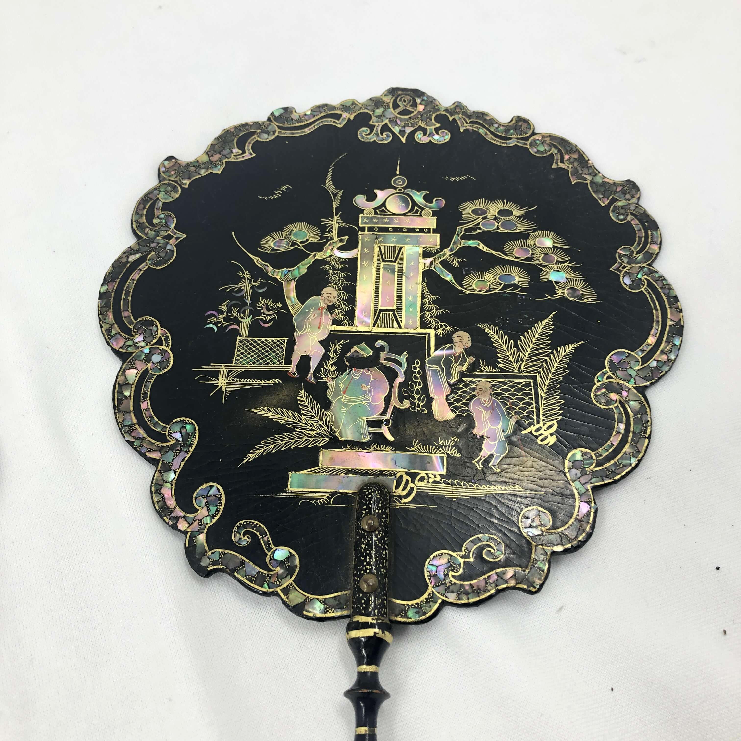 A pair of Victorian mother of pearl inlaid scalloped lacquered and chinoiserie decorated hand held fans with turned handles and gilt decorations.