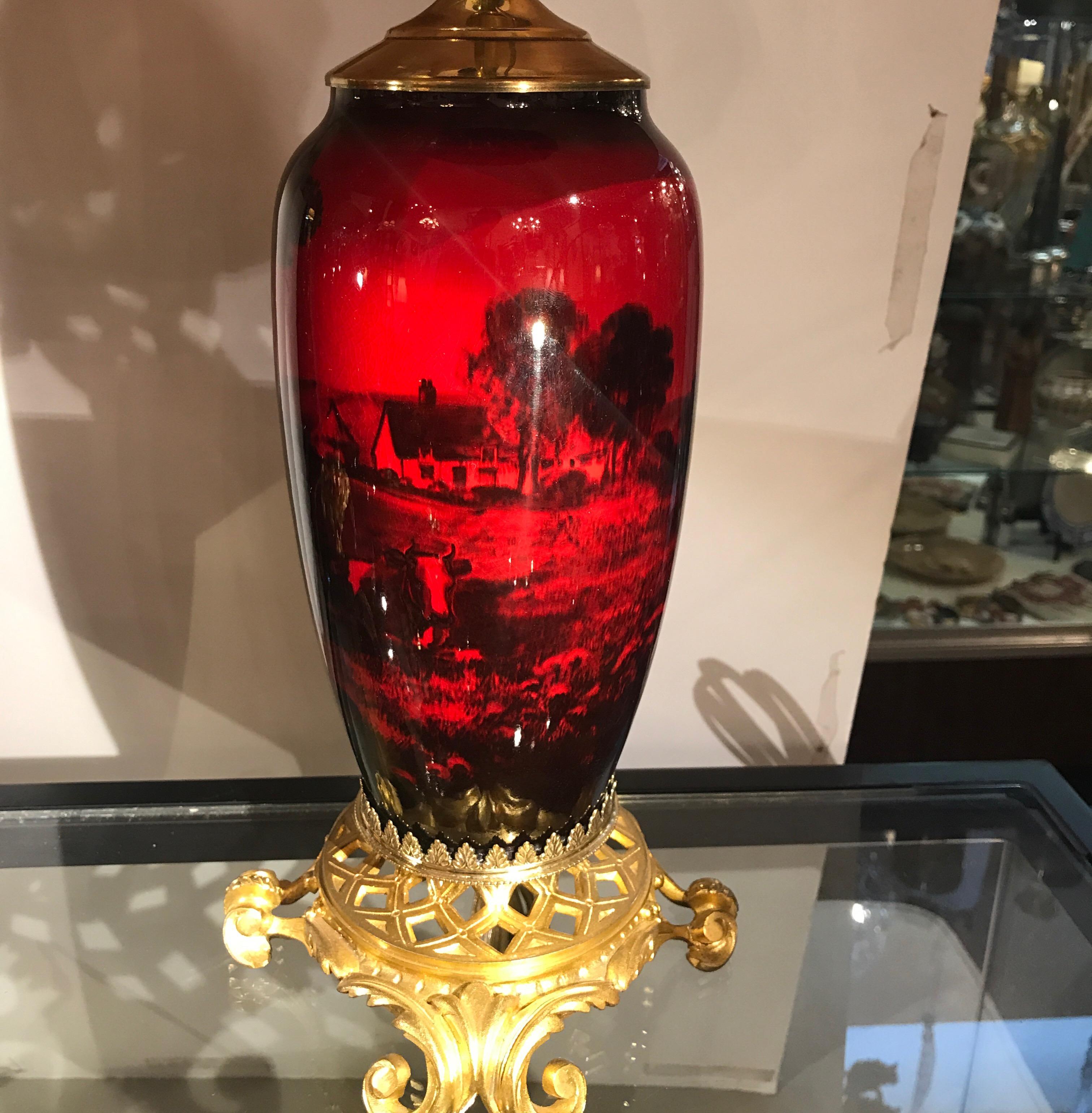 Exceptional pair of English flambe glazed ormolu-mounted lamps. Made by Royal Doulton in the early 20th century, these rich red glazed lamps are hand-painted by the top decorator, Charles Noke of the Royal Doulton porcelain and pottery makers. The