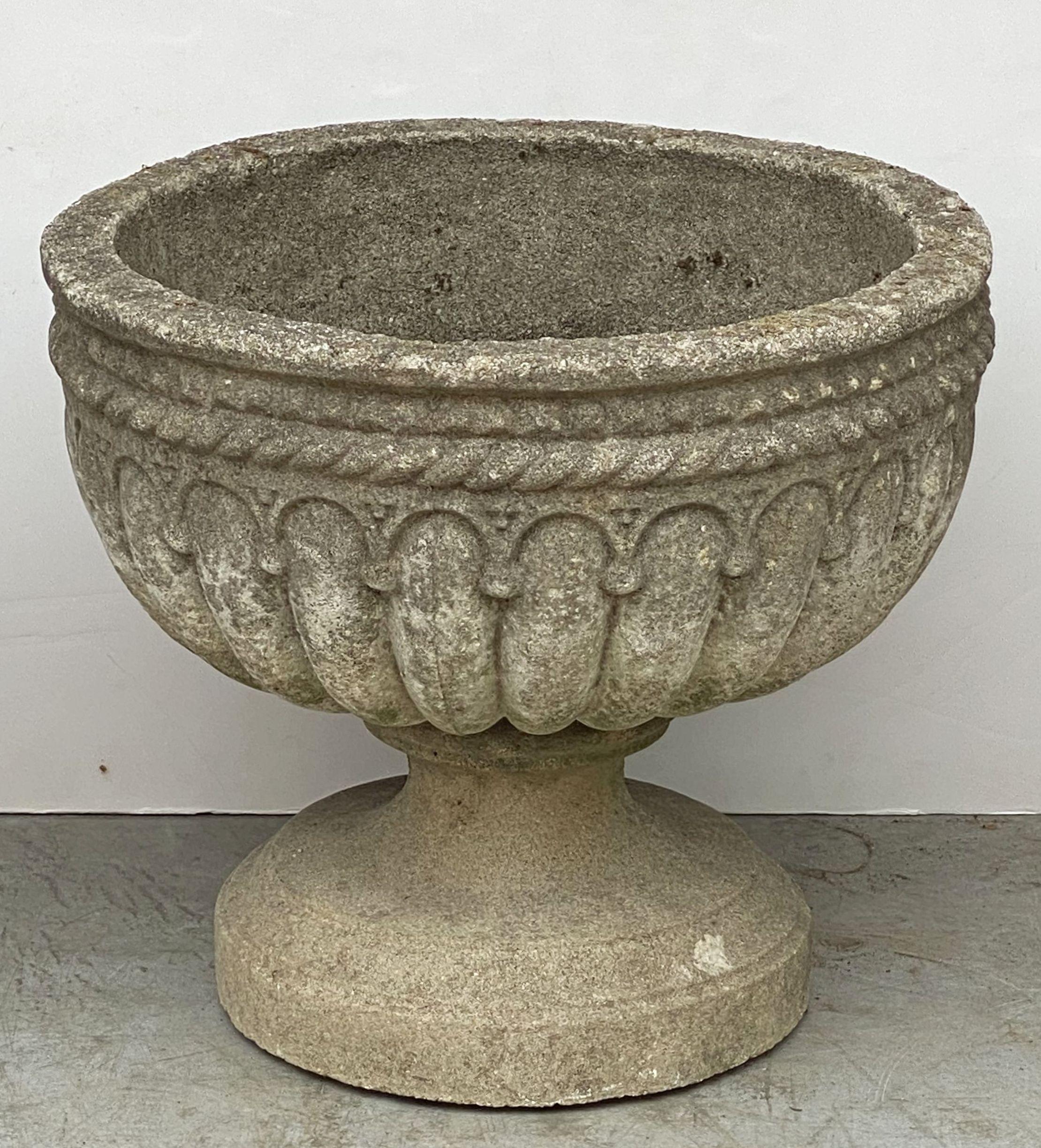 A fine pair of large English garden urns or planters of composition stone in the Classical style.
Each urn featuring a rolled rim edge over a lobed bowl on raised round base, with a braid design in relief around the circumference.

Dimensions of