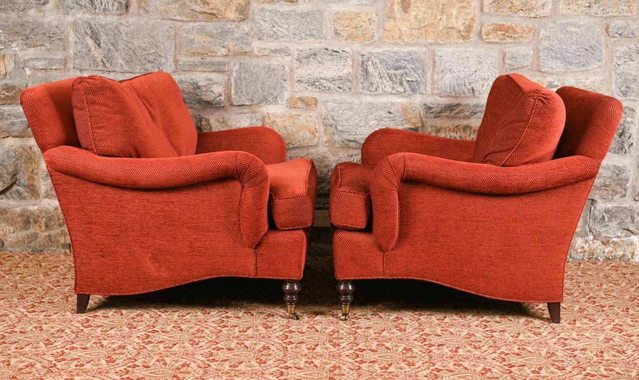 Pair of English George Smith lounge chairs. The chairs are oversized, has the original fabric with wood legs and brass casters.
