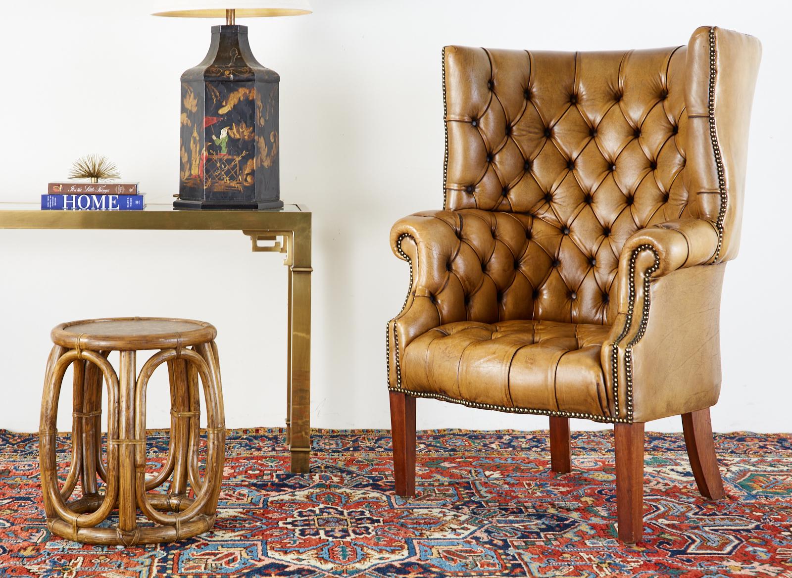 Rare pair of handsome English porters wingback armchairs or library chairs made in the Georgian taste. Featuring a rich, tufted brown cigar leather upholstery that has faded into a warm cafe ole tone. The leather is bordered with brass tack nail