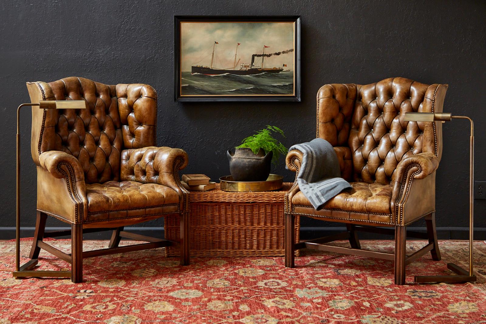 Fine pair of English wing chairs or library chairs featuring an aged cigar leather tufted upholstery. The wingbacks have a mahogany hourglass frame made in the George III taste with fully developed wings and straight, square legs in front. Crafted
