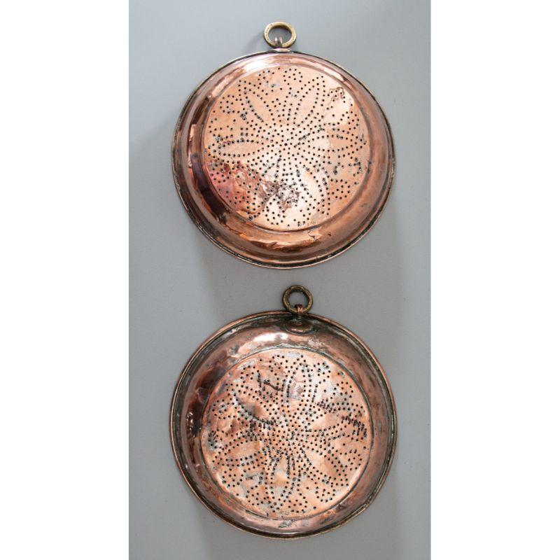 A fine pair of antique Georgian copper and brass colanders or sieves. These large sieves are hand forged and heavy with a beautiful old copper patina and floral design. They have brass rings for hanging and would be a charming addition to your